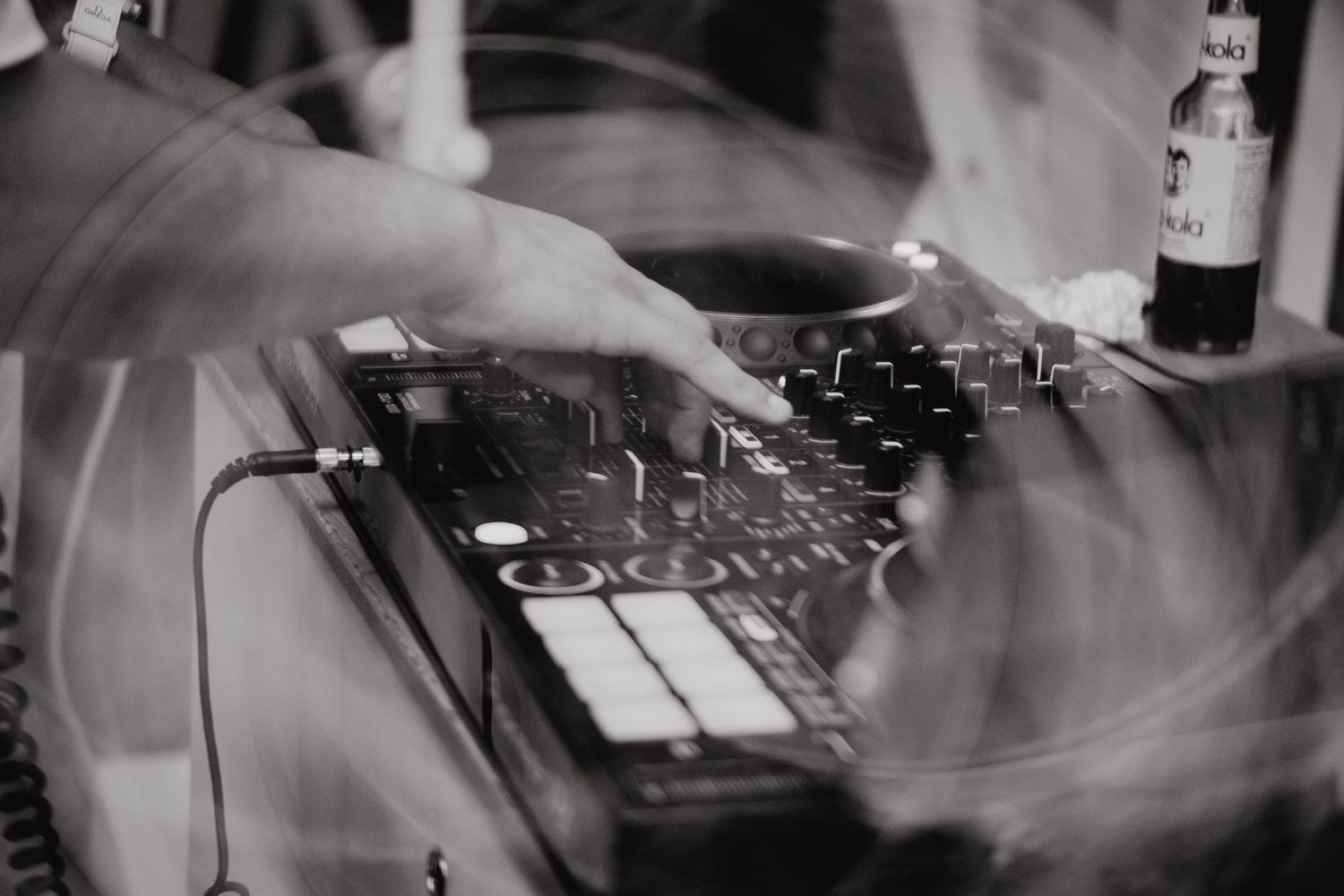 Close-up of hands operating professional DJ equipment and mixer controls at a nightclub or music event.