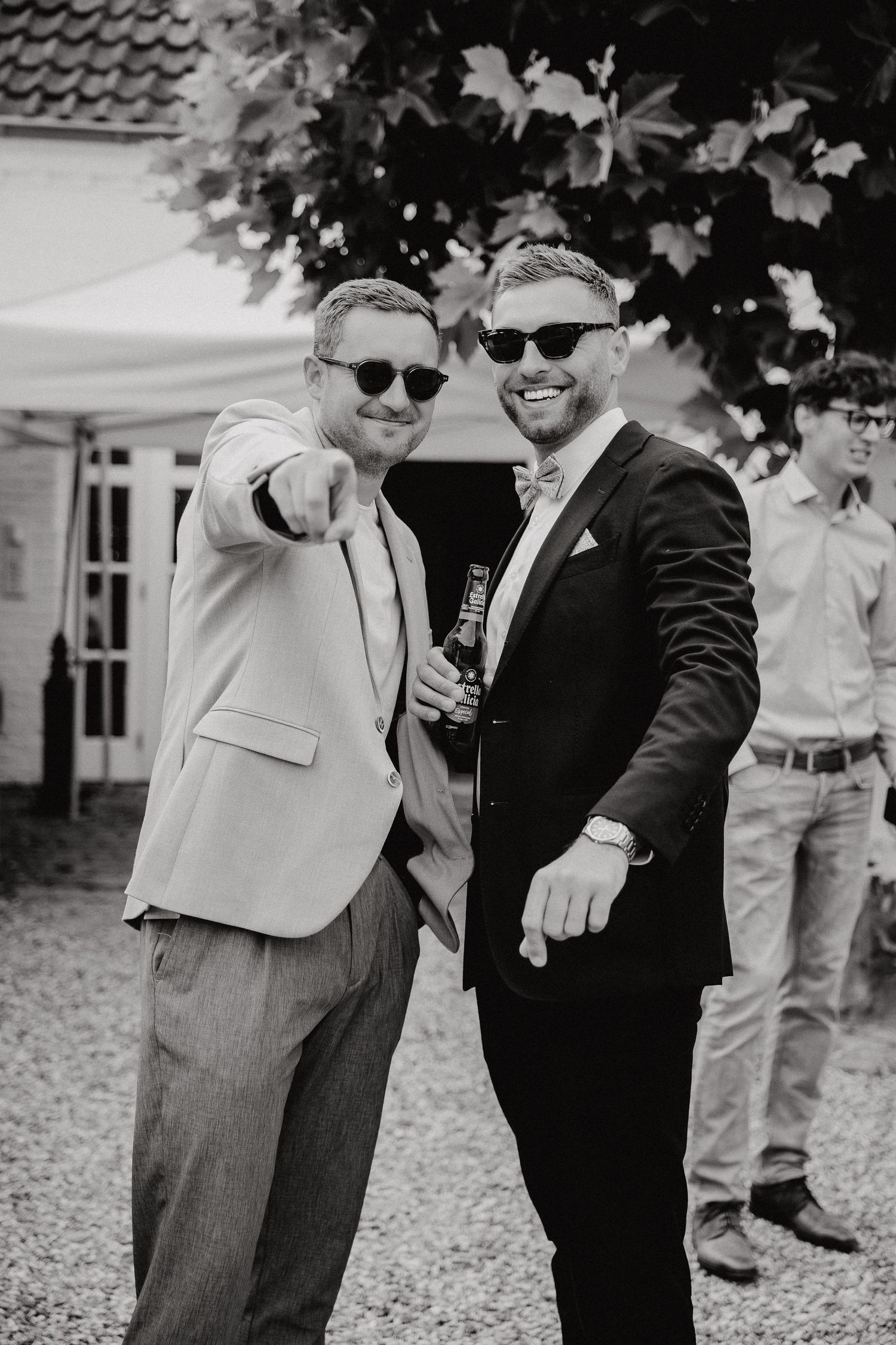 Black and white photo of wedding guests in sunglasses enjoying outdoor celebration.