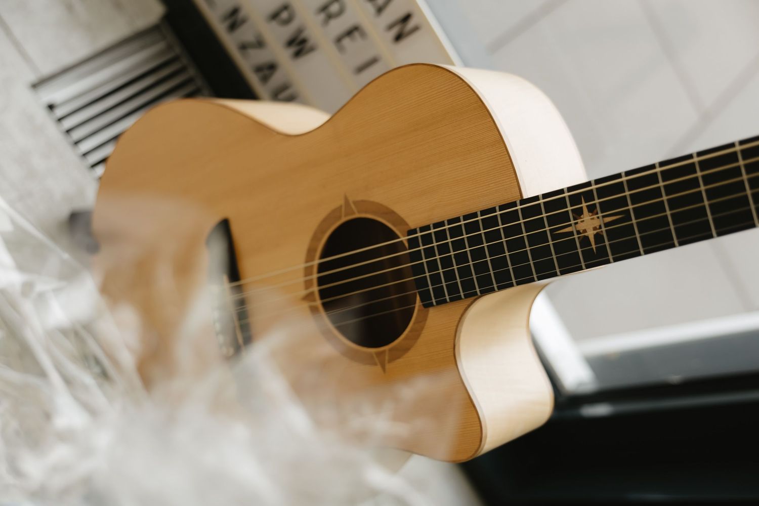 Close-up view of a natural wood acoustic guitar with smoke or vapor drifting across the frame.
