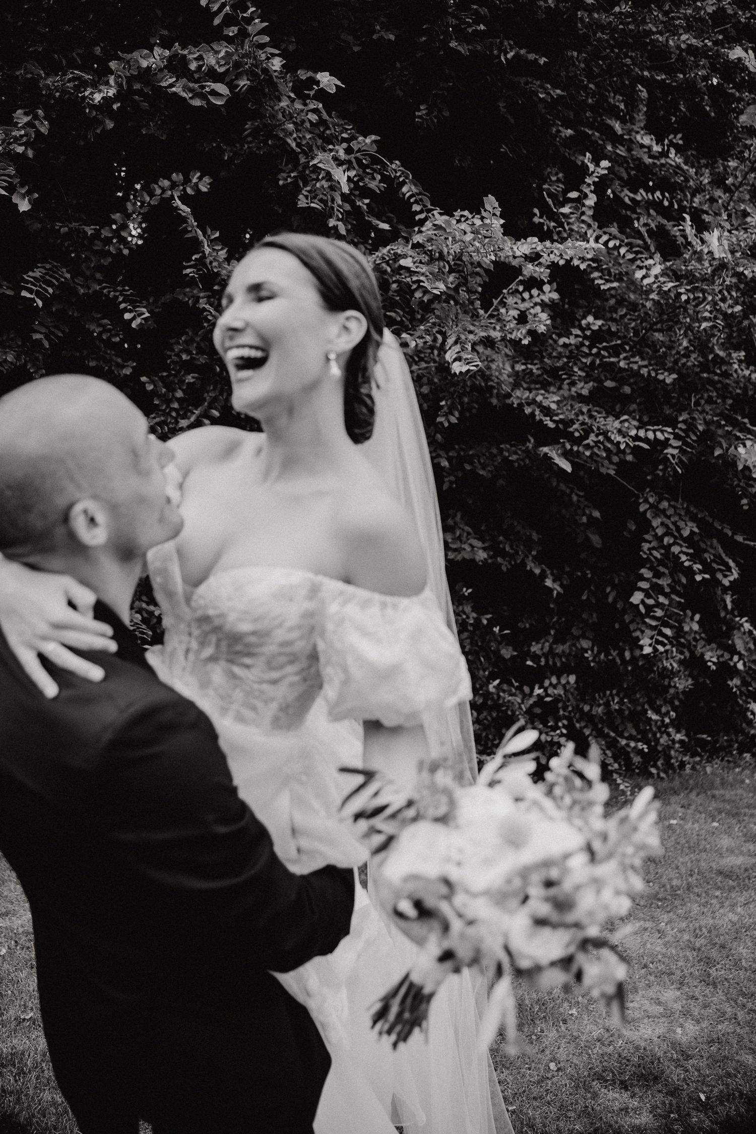 Black and white photo of newlyweds sharing playful moments during their wedding photoshoot.