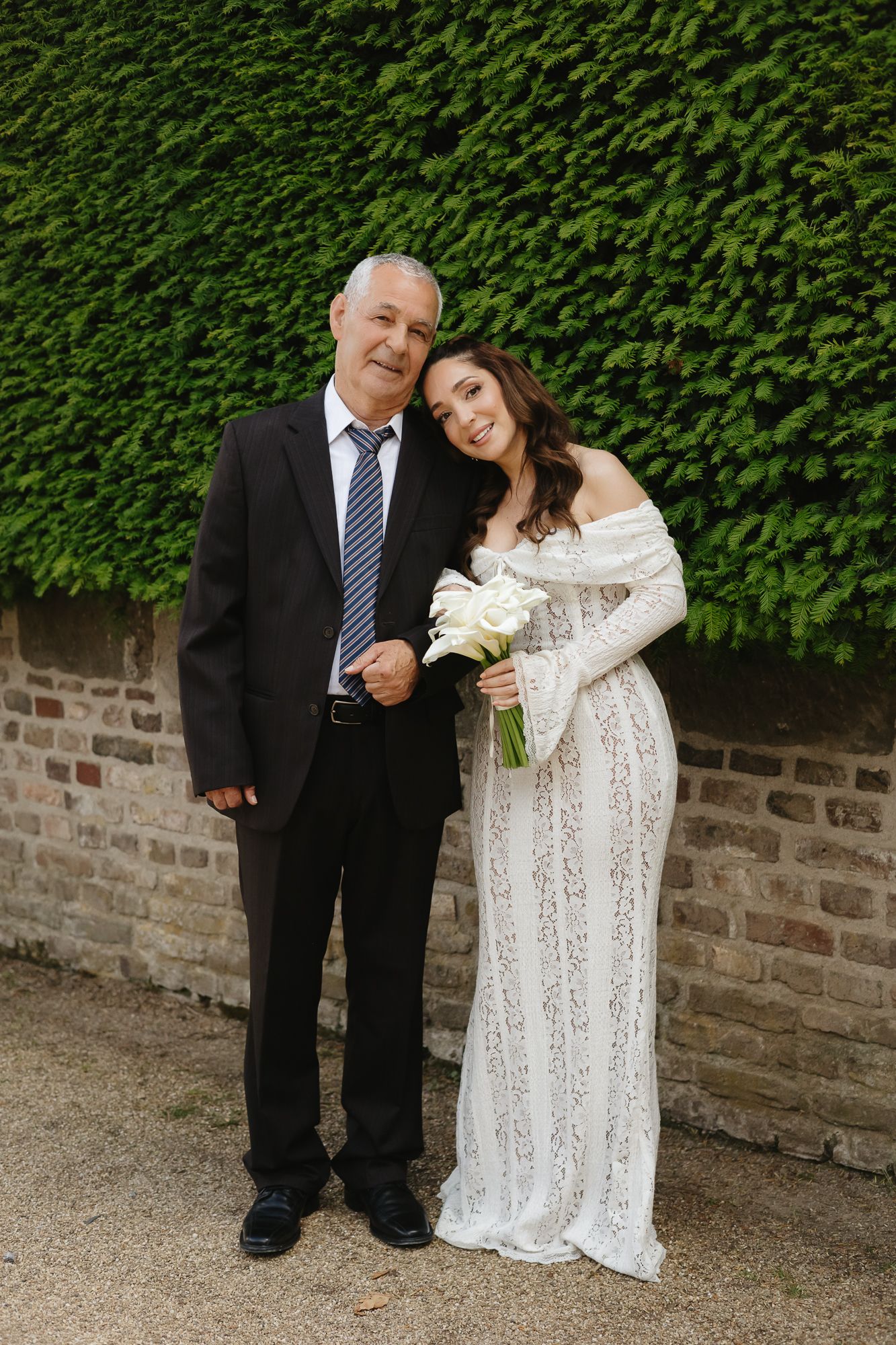Sweet moments captured against a stone wall and green hedge backdrop.