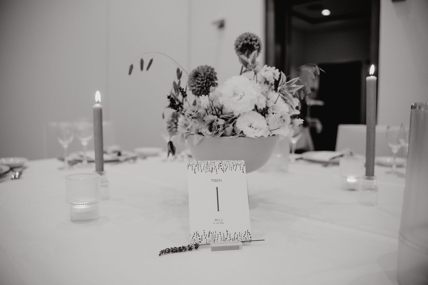 A black and white photo of wine bottles and table settings arranged for a wedding reception.