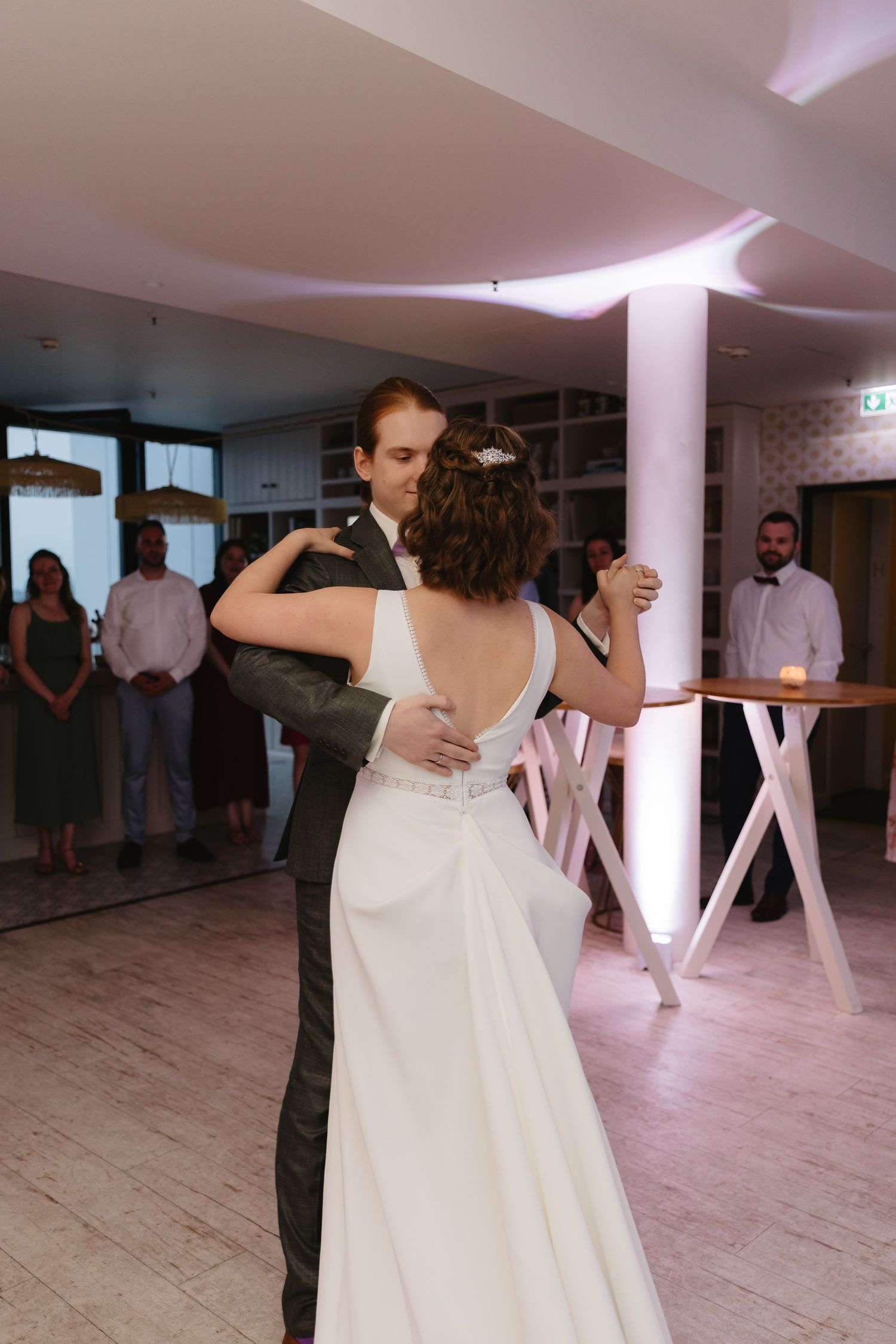 Couple performs a romantic dance move at a wedding reception, with the bride's white dress flowing gracefully.