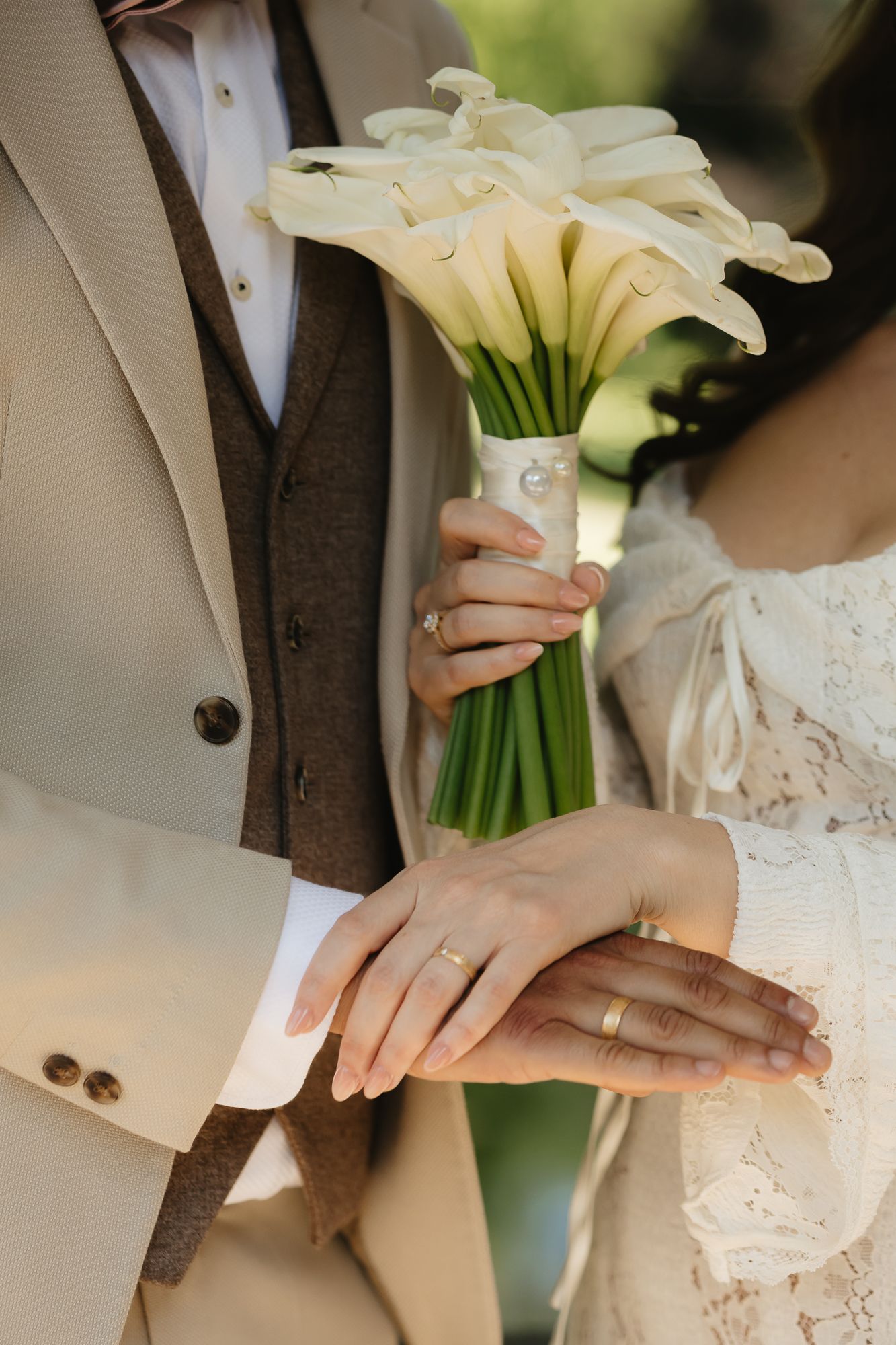 Wedding detail shots showing rings, hands, and white calla lily bouquet.