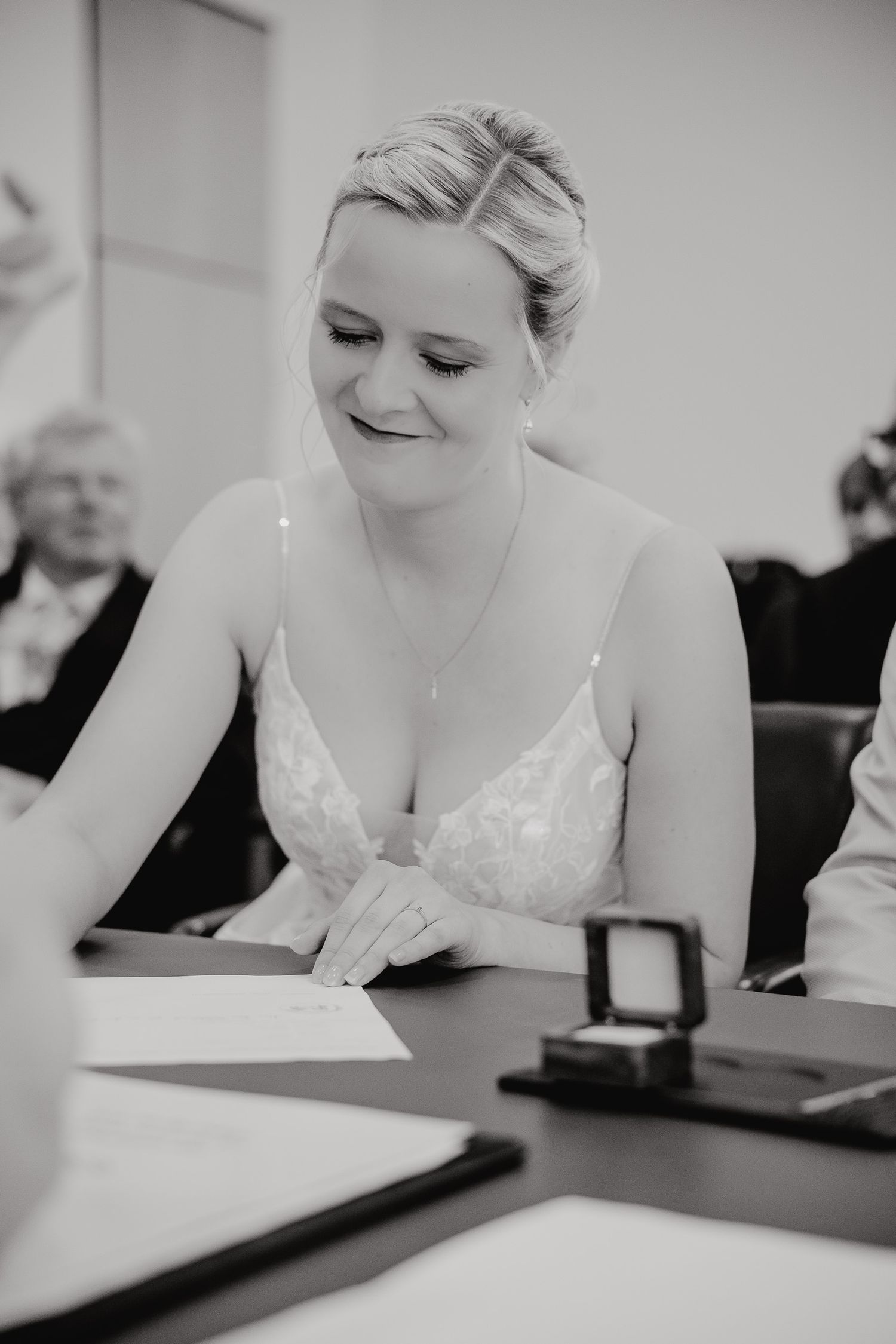 Black and white photo series showing a bride signing marriage documents at a table.