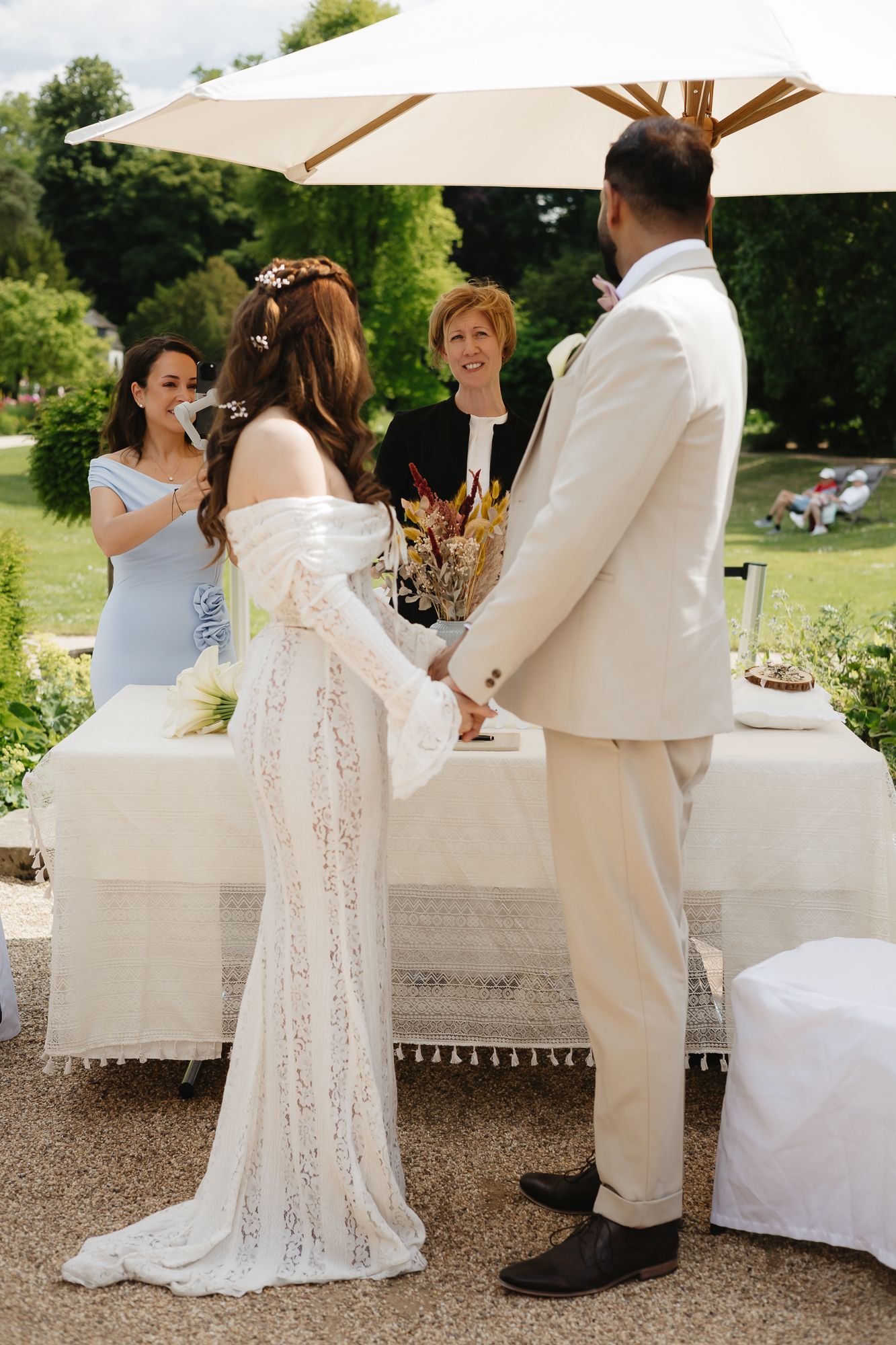 Wedding ceremony setup with white umbrellas and elegant decor in outdoor garden setting.