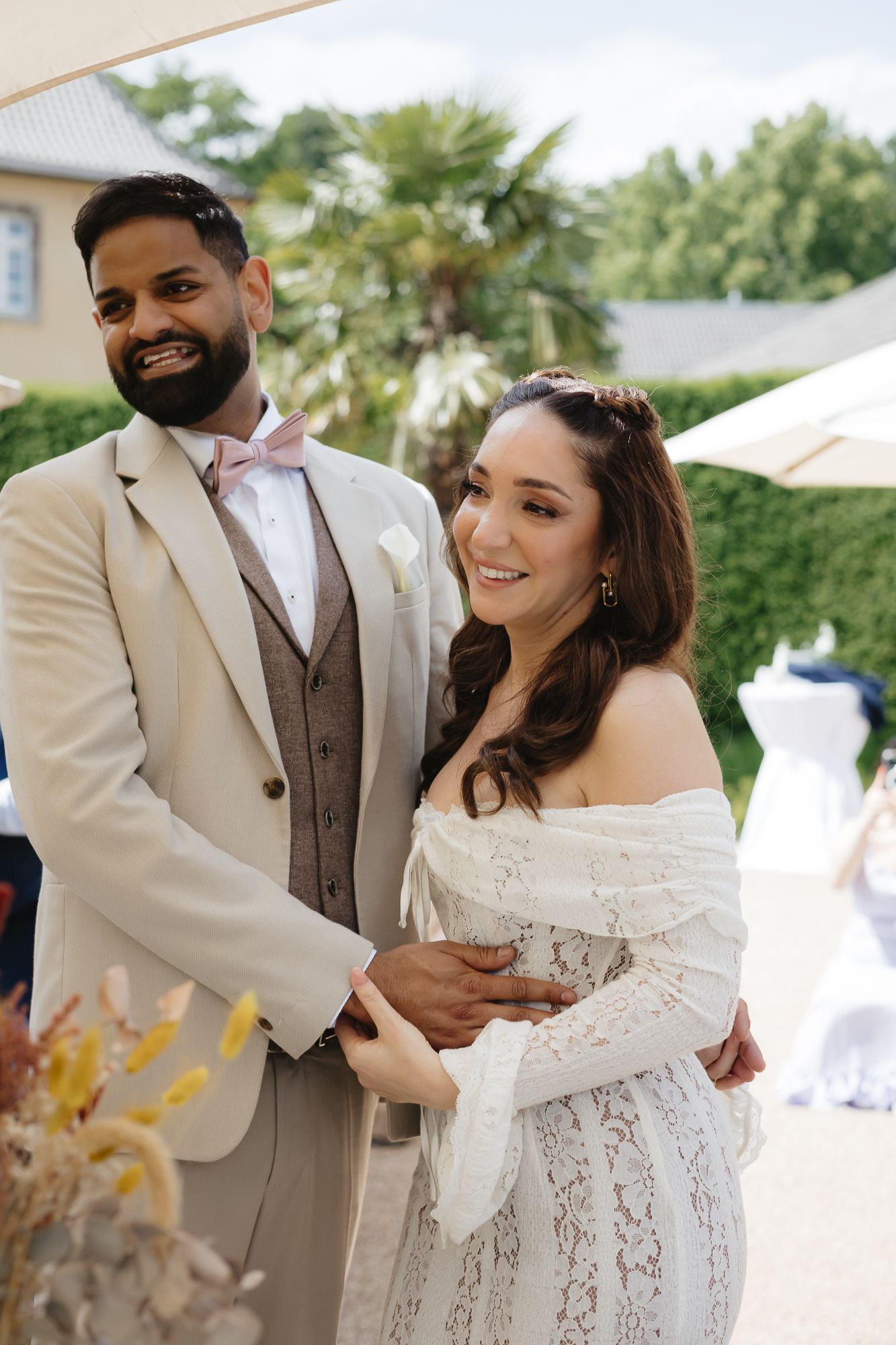 A couple in wedding attire signs documents together during an outdoor ceremony.