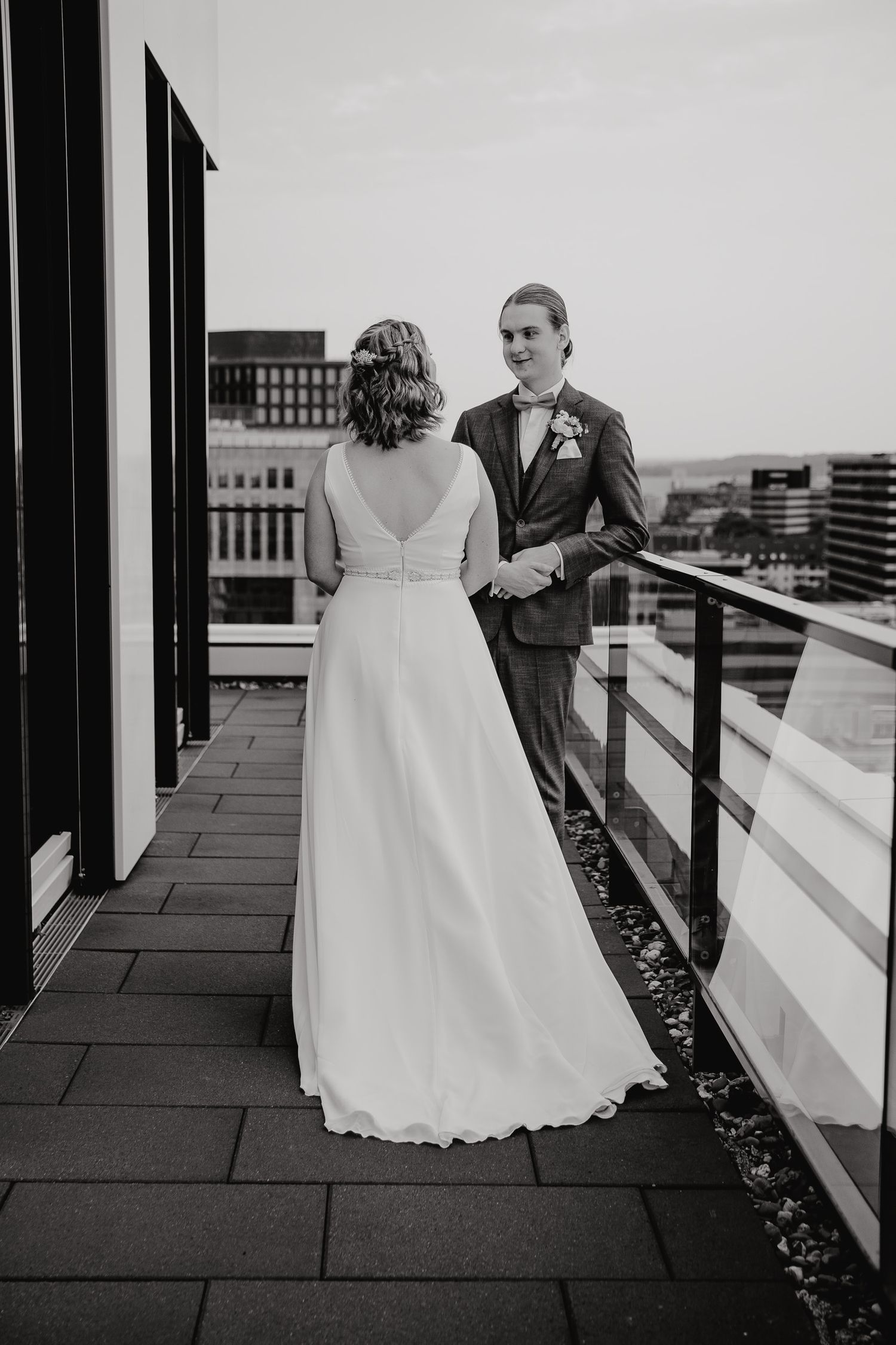 Black and white wedding photos show tender moments between couple on a porch with white railings.