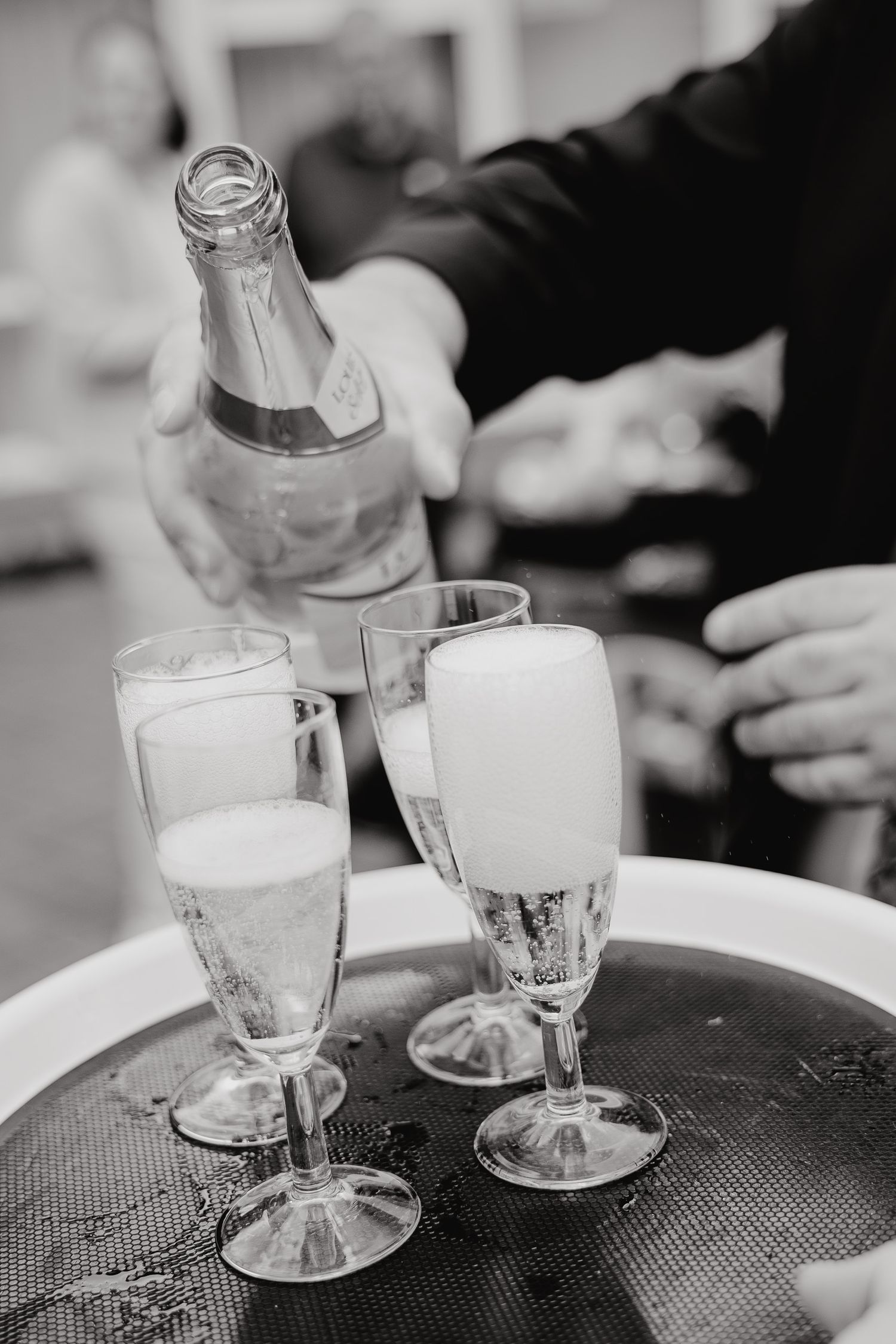 Black and white image of water glasses being served on a textured surface.