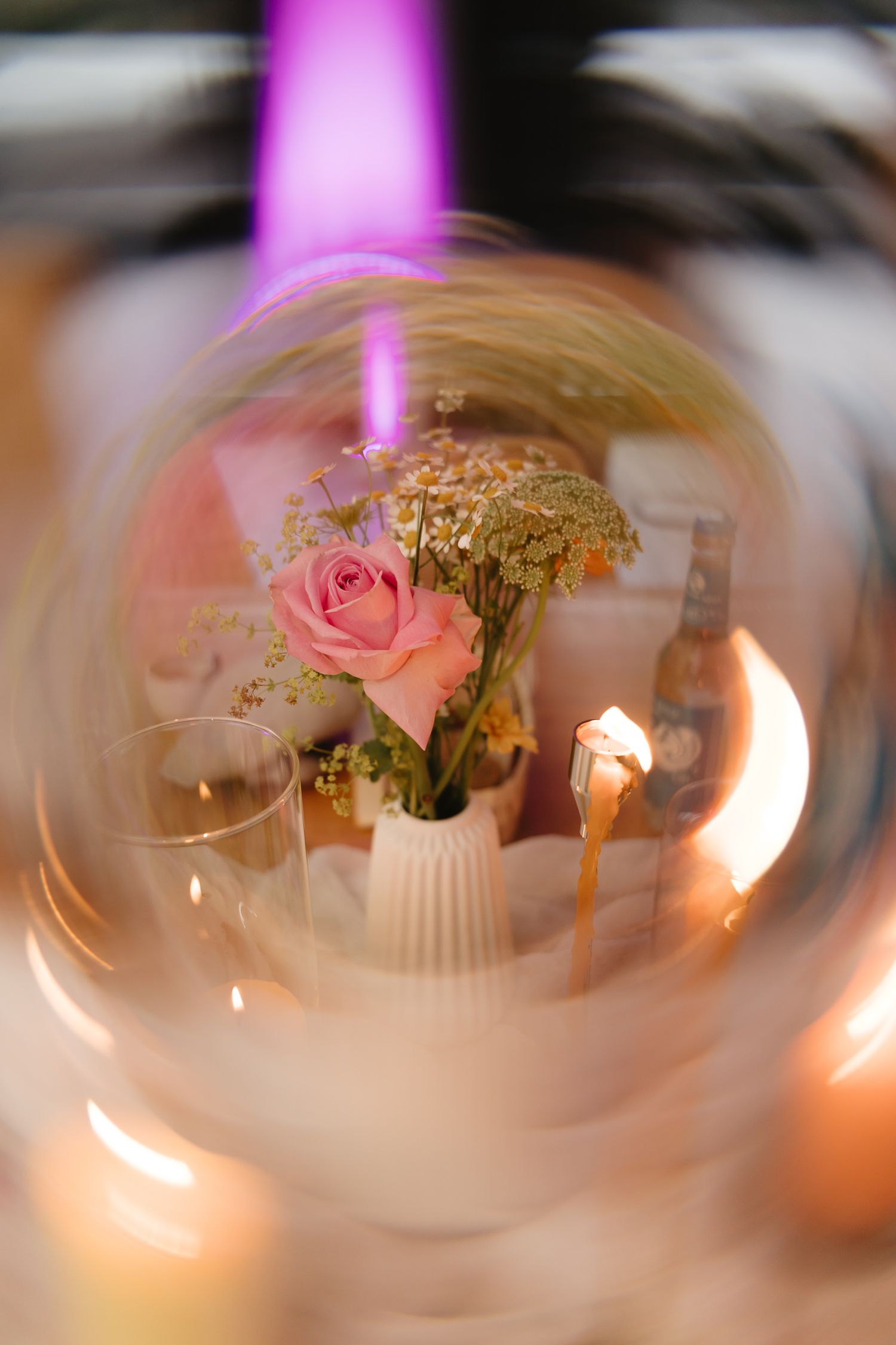 Soft focus wedding centerpiece with pink roses and candlelight creating romantic ambiance.