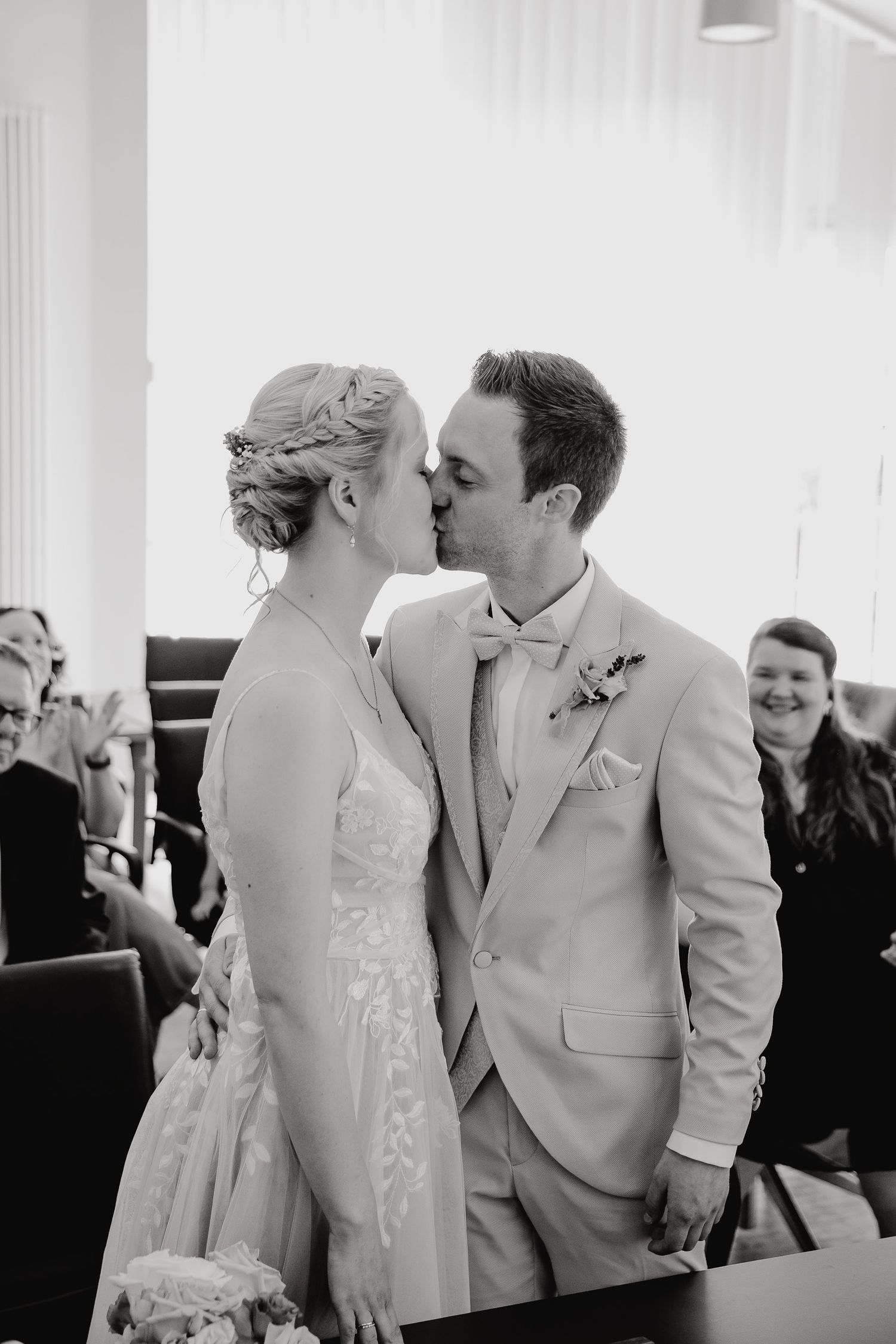 Black and white wedding photo series showing a romantic first kiss between newlyweds at the altar.