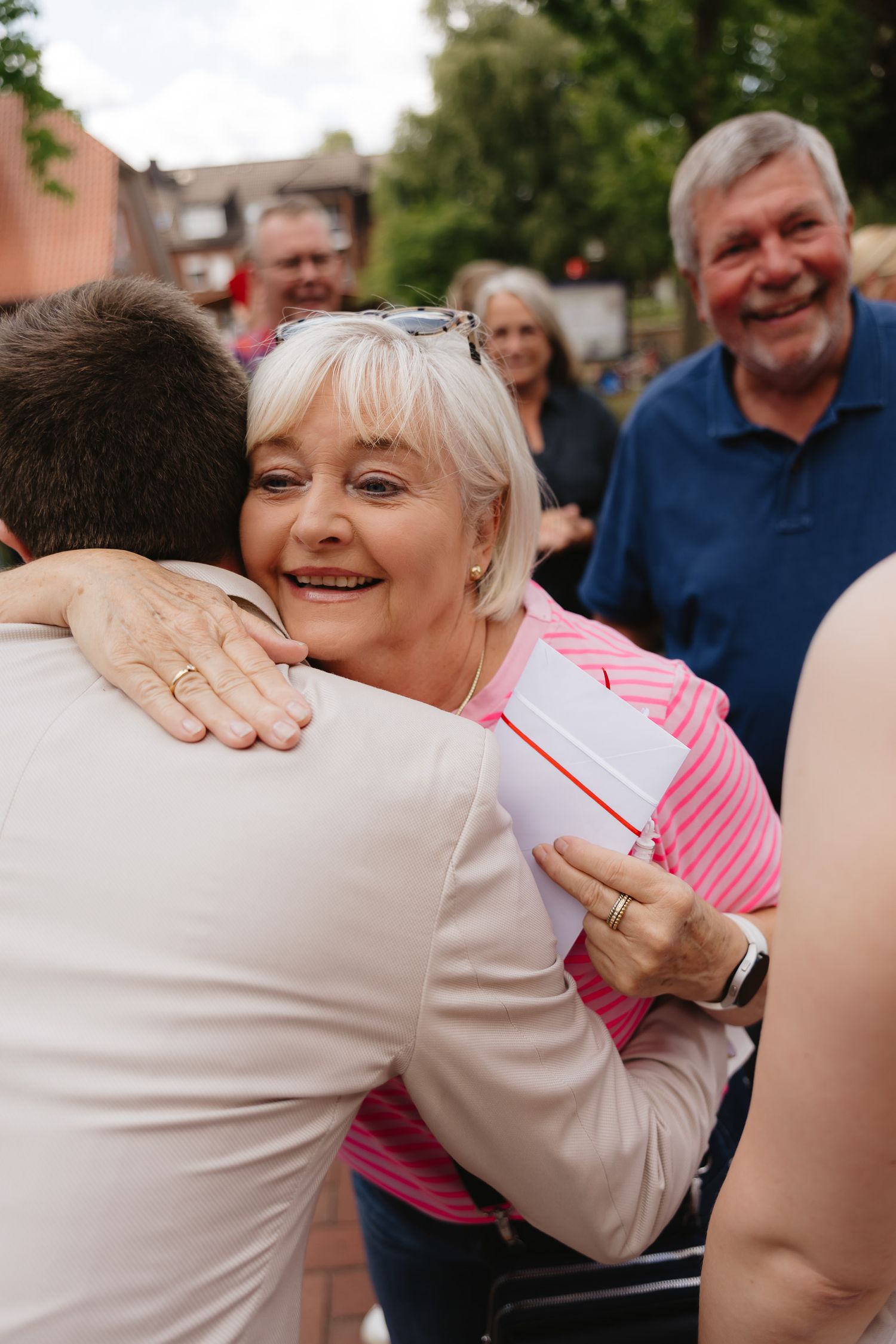 A series of candid photos showing people embracing and hugging at an outdoor gathering or celebration.