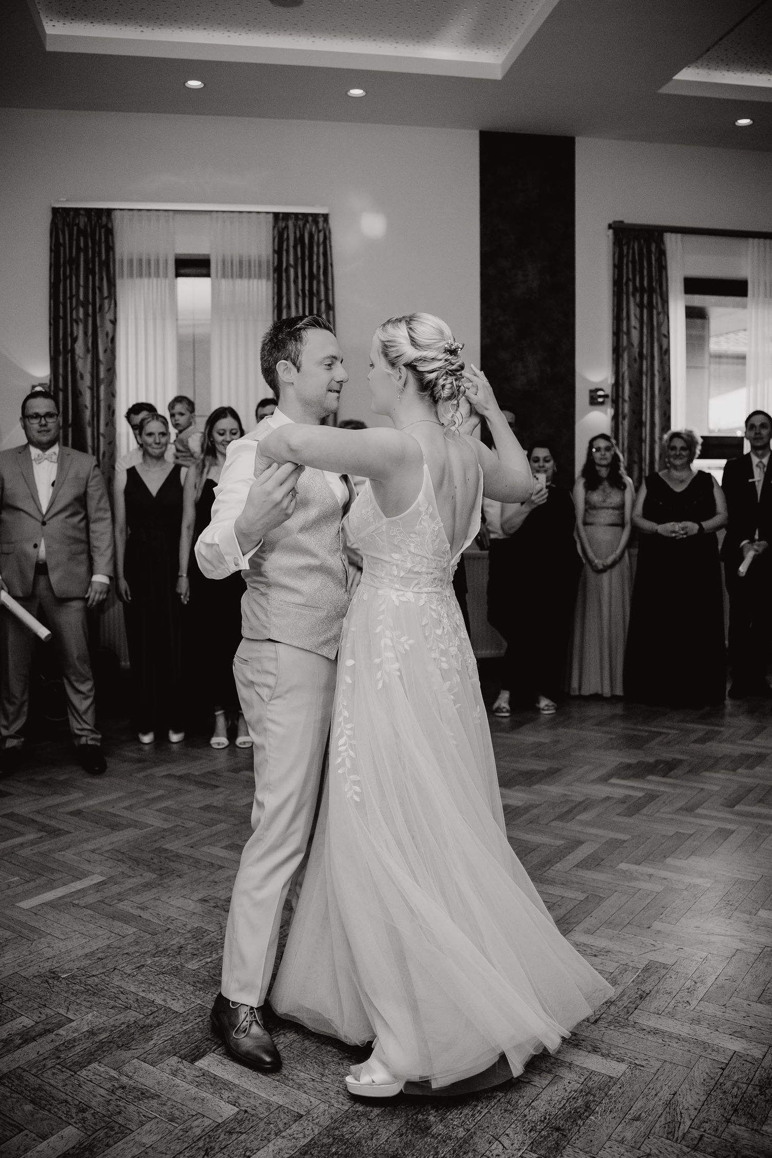 Black and white photo series of newlyweds dancing their first dance at a wedding reception with guests watching.