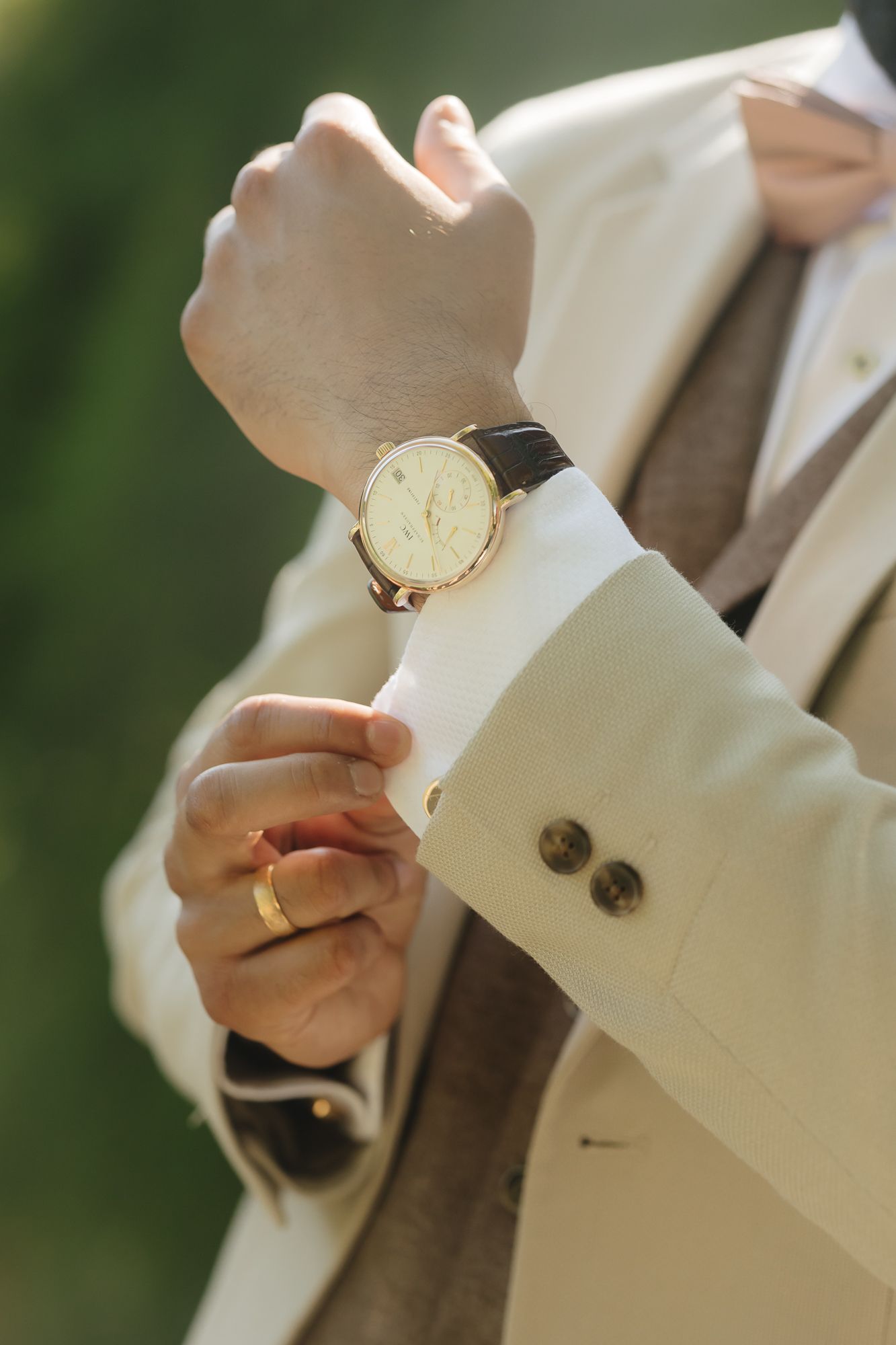 Close-up of white dress shirt cuffs and cufflinks being adjusted.