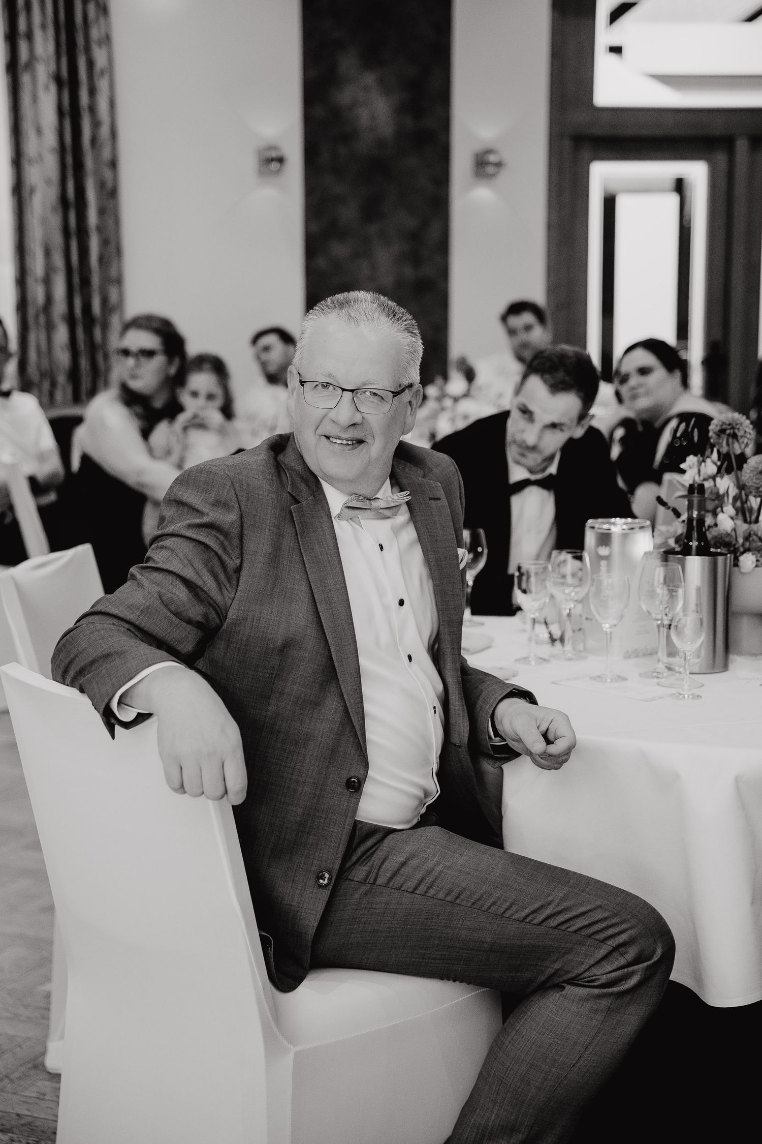 A sequence of black and white photos showing a guest at a wedding reception laughing and reacting with joyful expressions.