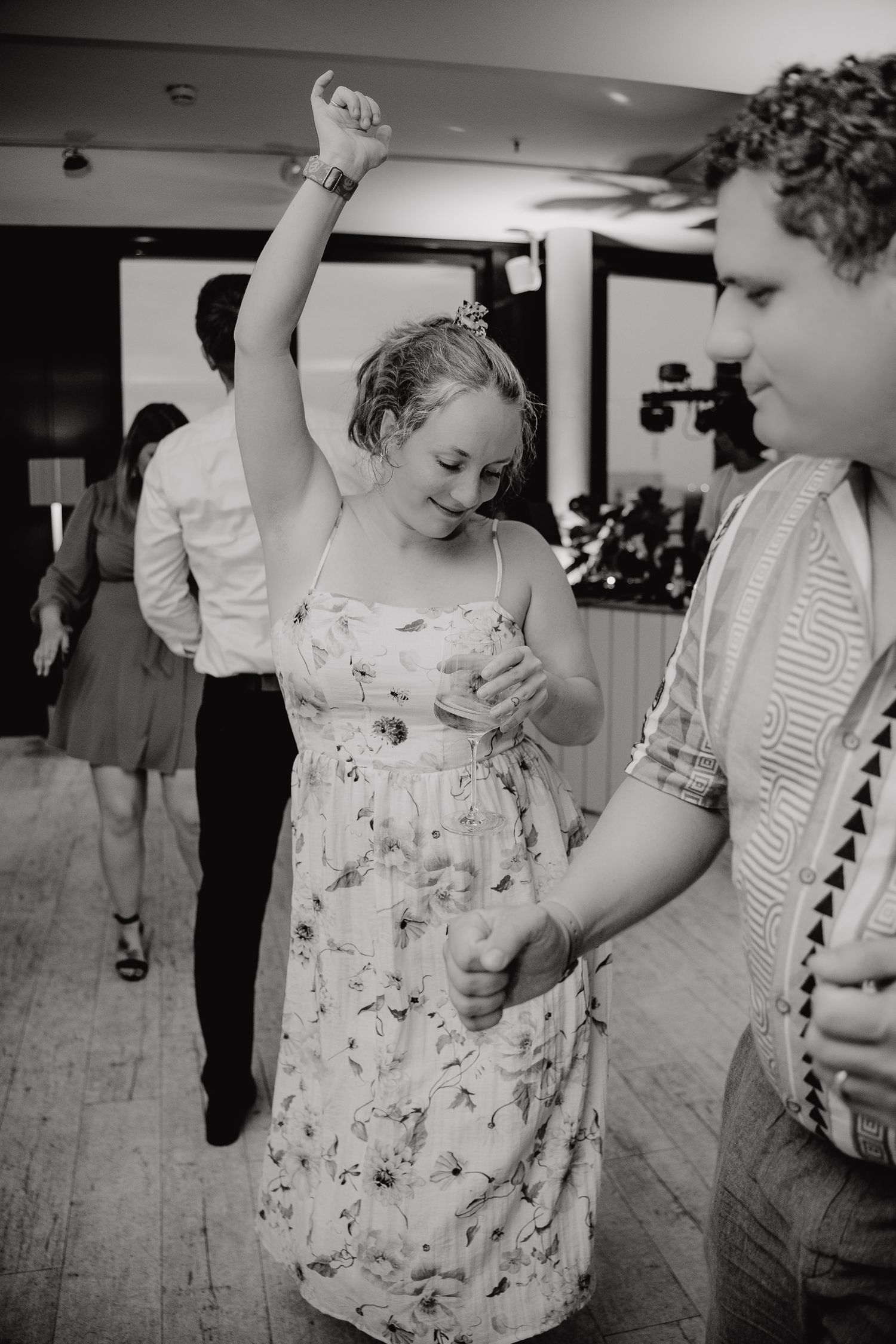 Black and white photo sequence shows people dancing and moving energetically on a wooden floor at a social gathering.