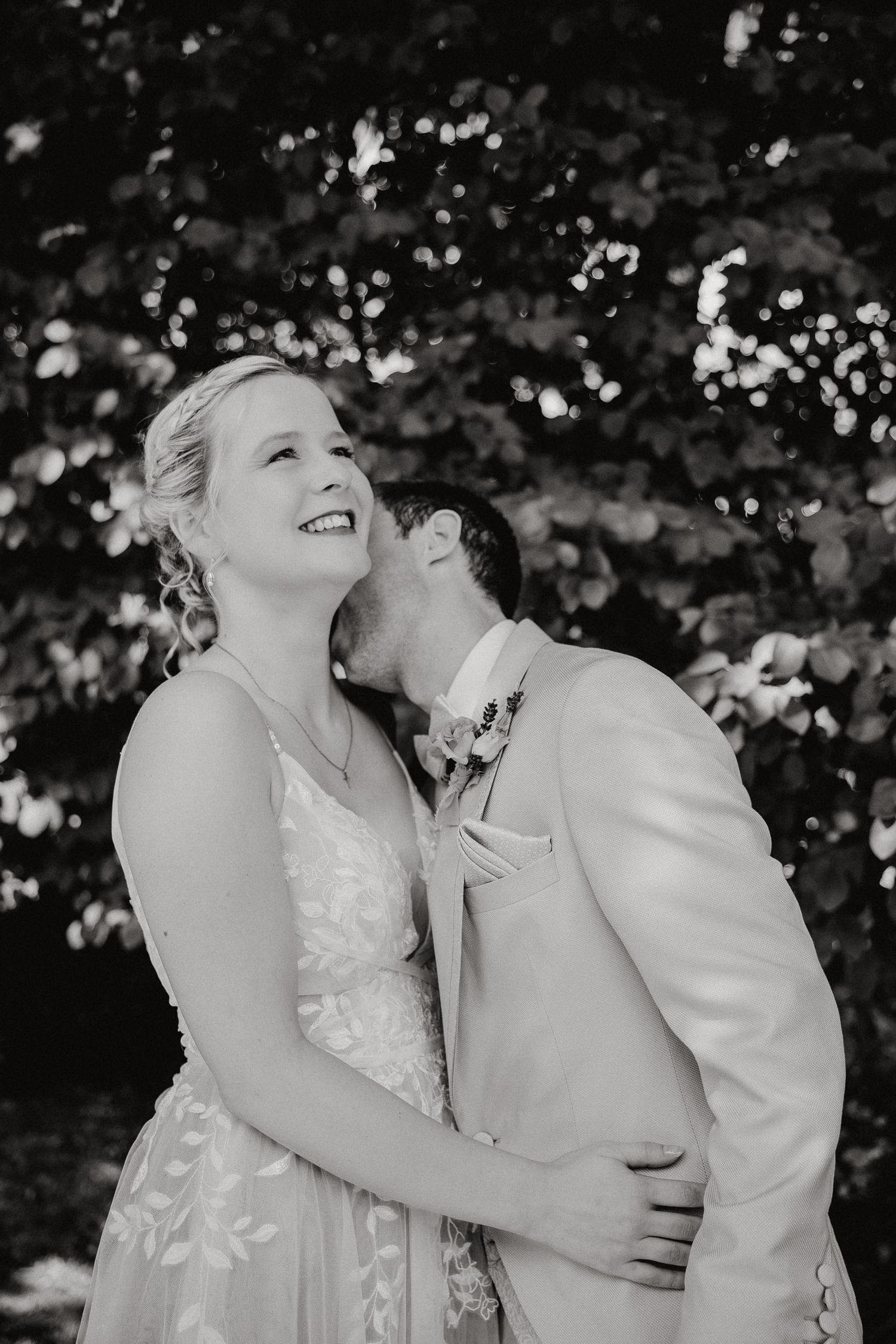 Black and white photo series of a joyful couple laughing and embracing during an outdoor wedding photoshoot.