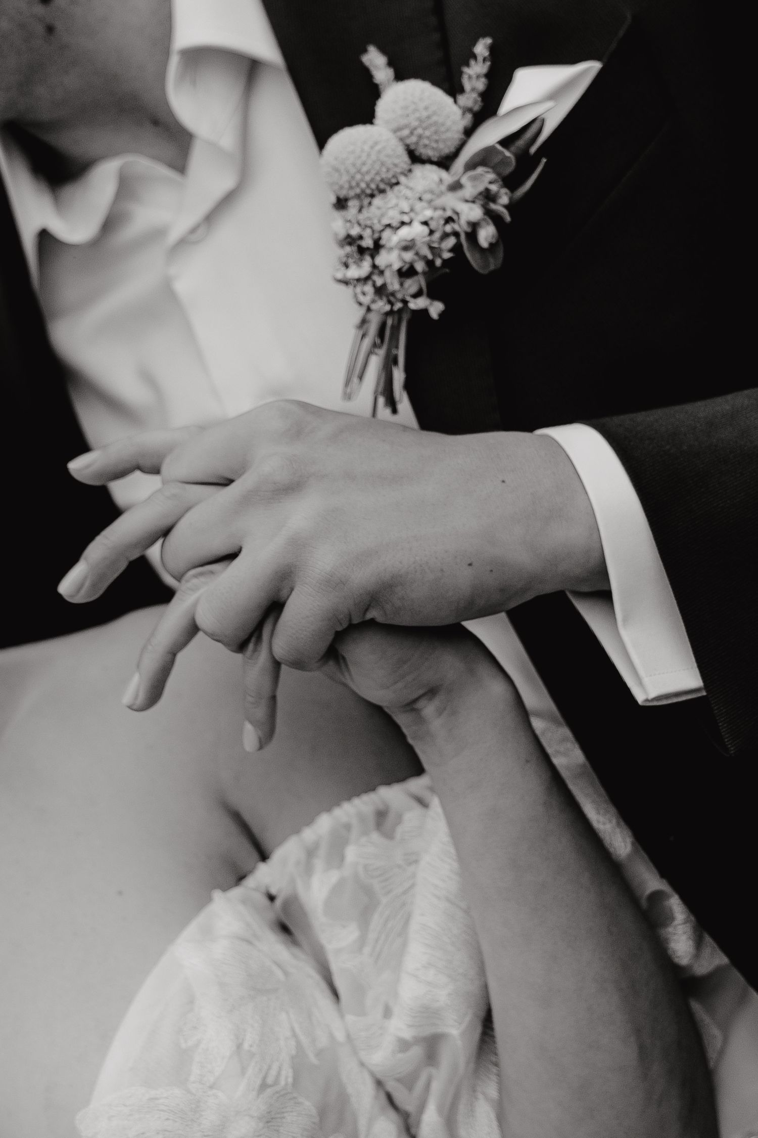 Black and white close-up of hands holding during wedding ceremony.