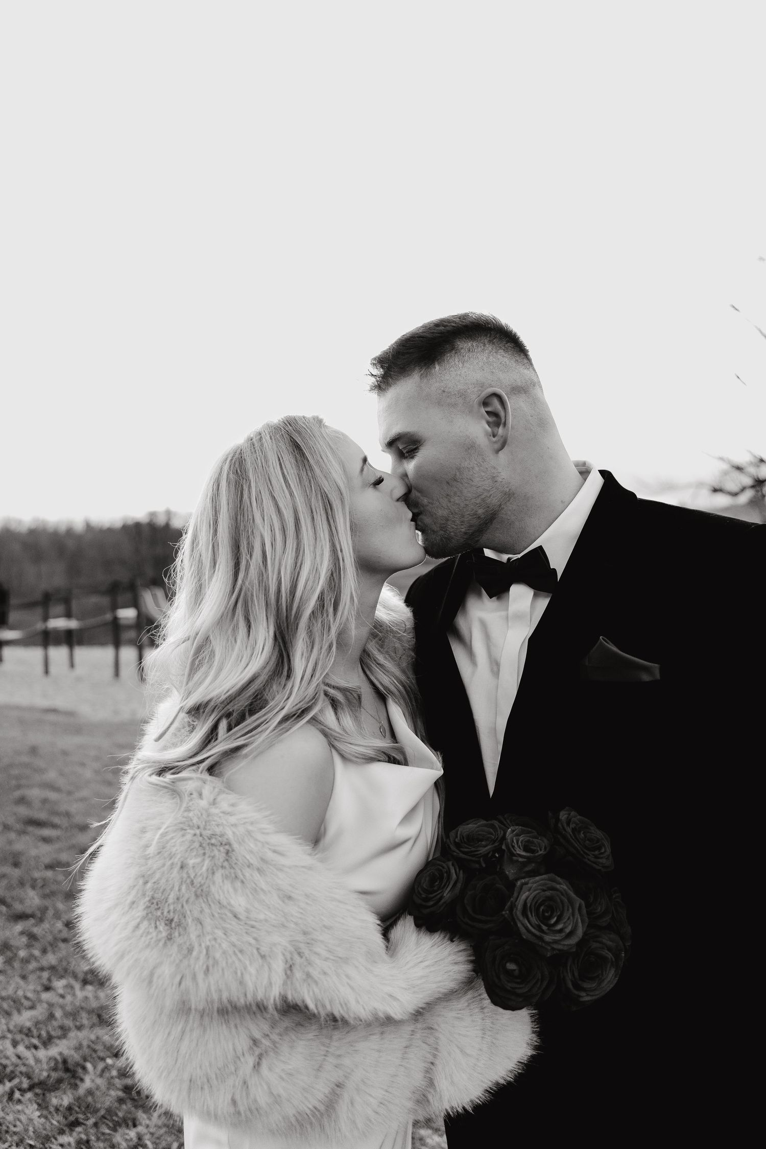 Intimate black and white portrait of couple sharing romantic moment outdoors.