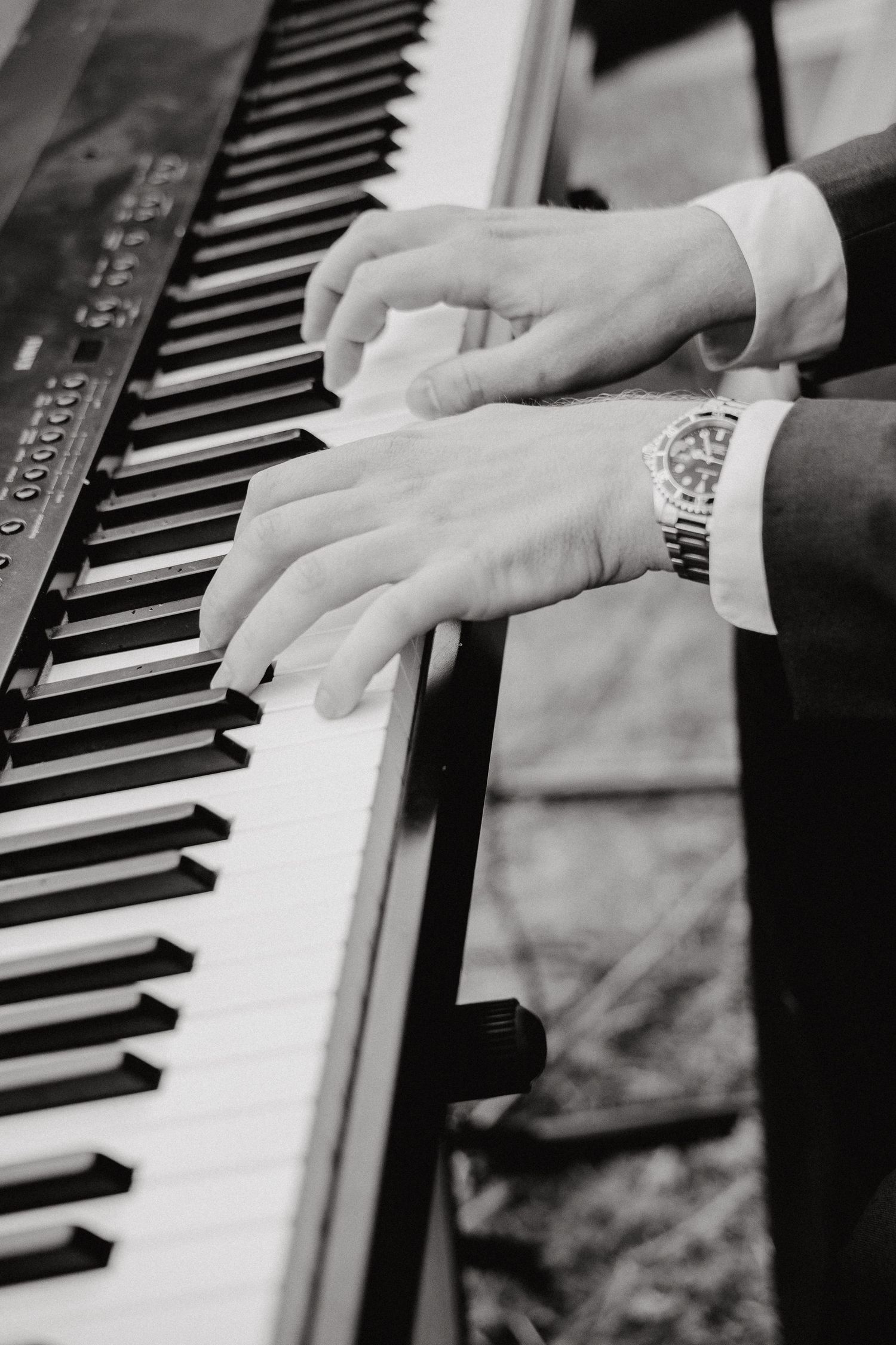 Close-up shots of hands playing piano keys in black and white.