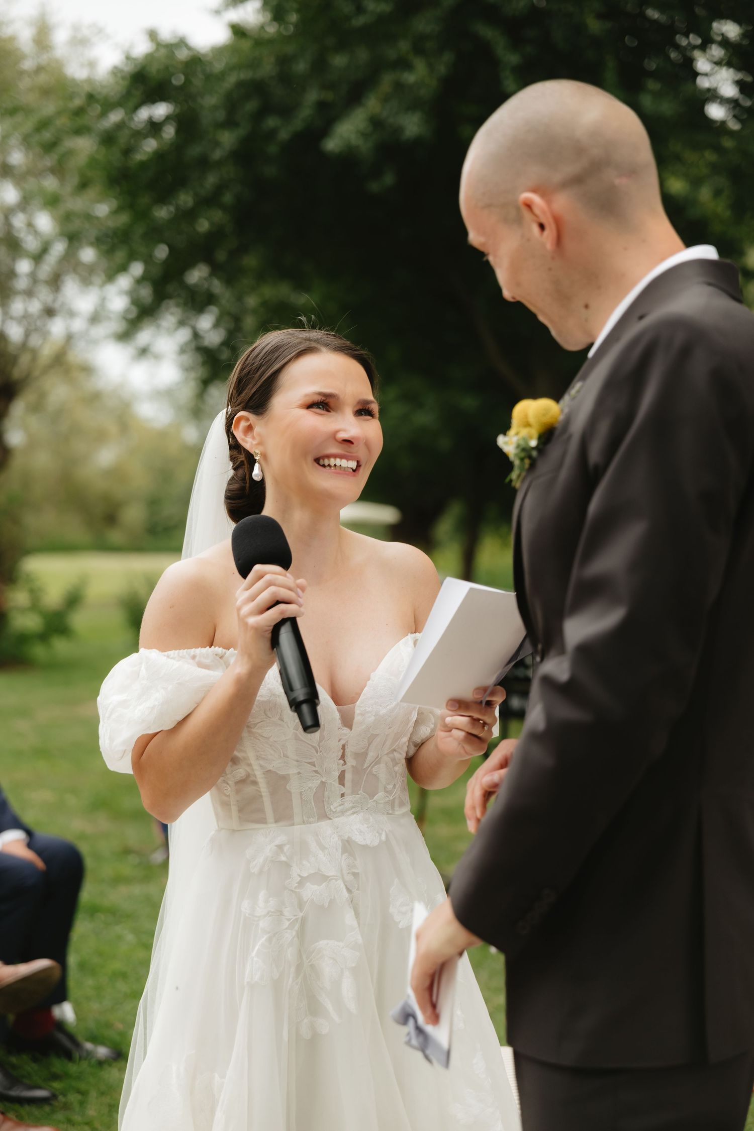 Couple exchanging vows during outdoor wedding ceremony with white decor.