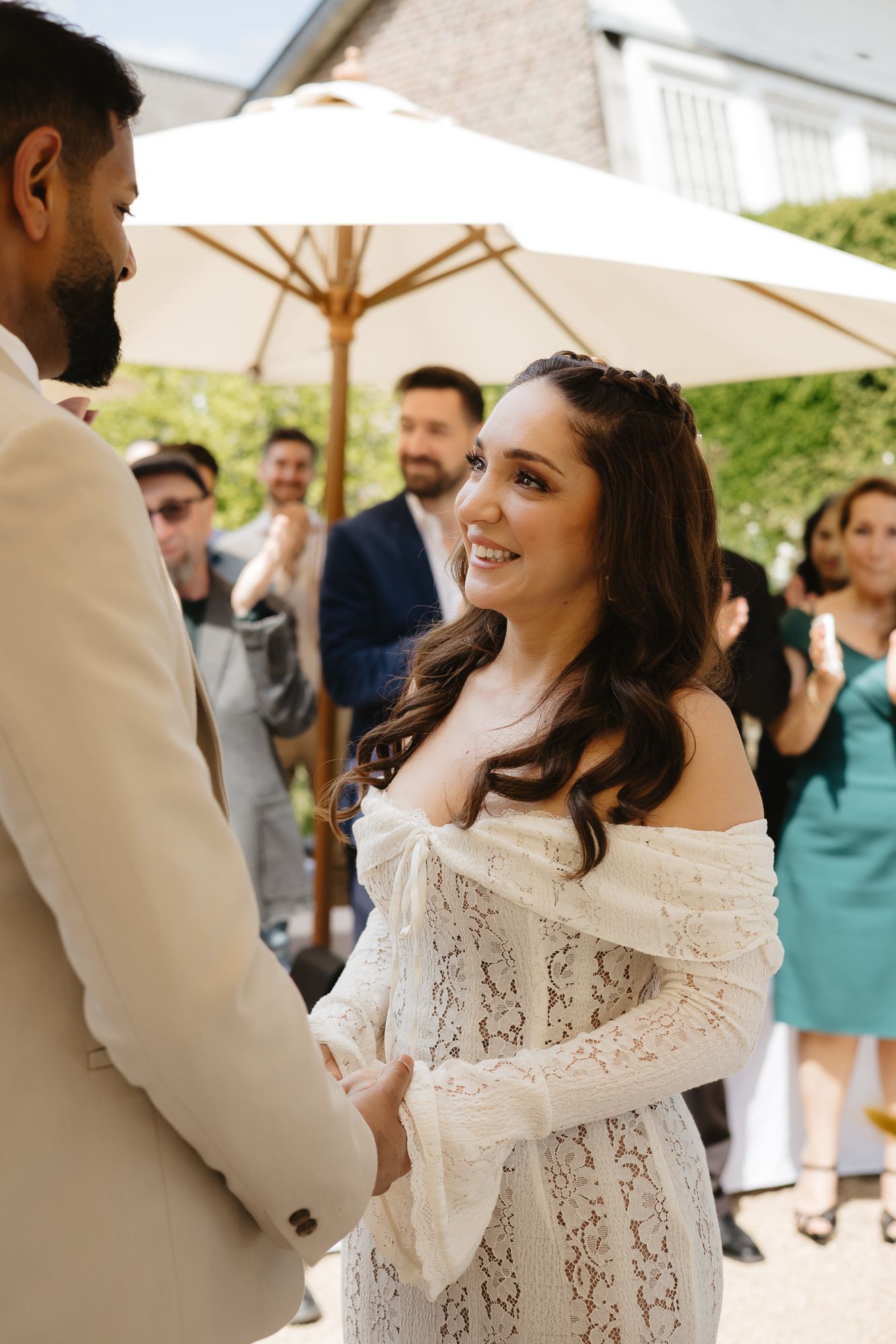 Emotional reactions captured during outdoor wedding ceremony with white umbrellas and lace dress details.