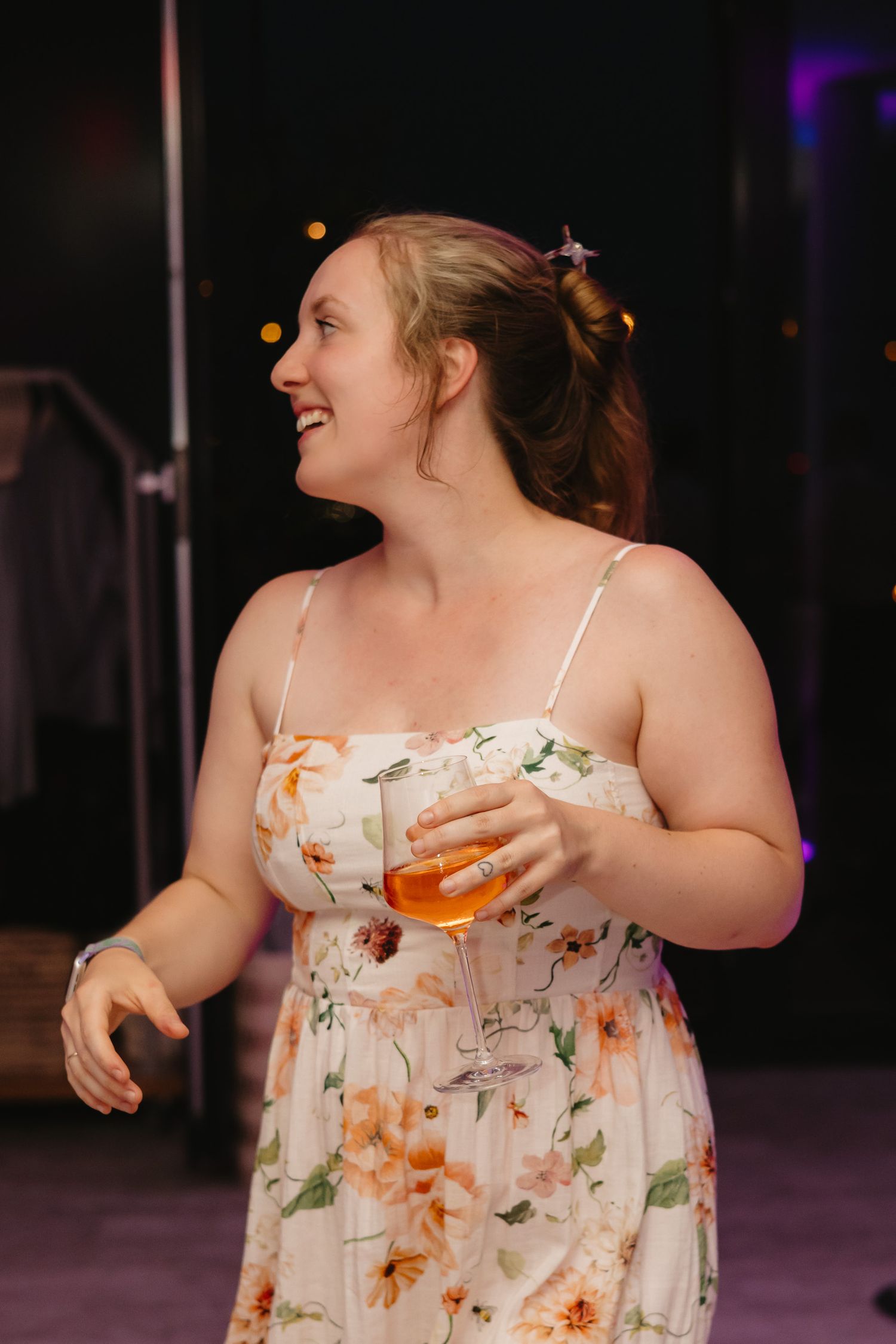 A person in a floral sundress dances joyfully against a dark background.