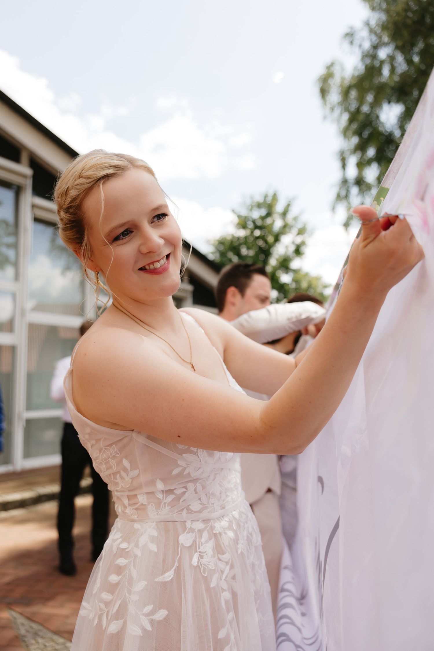 Person in a white lace dress outdoors enjoying a sunny celebration.