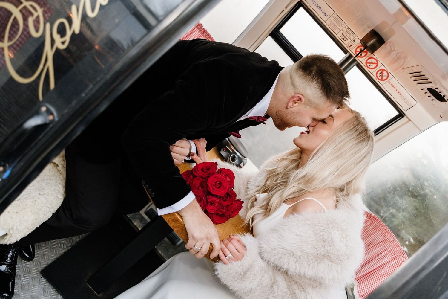 Romantic wedding couple sharing intimate moments with red roses and delicate details.