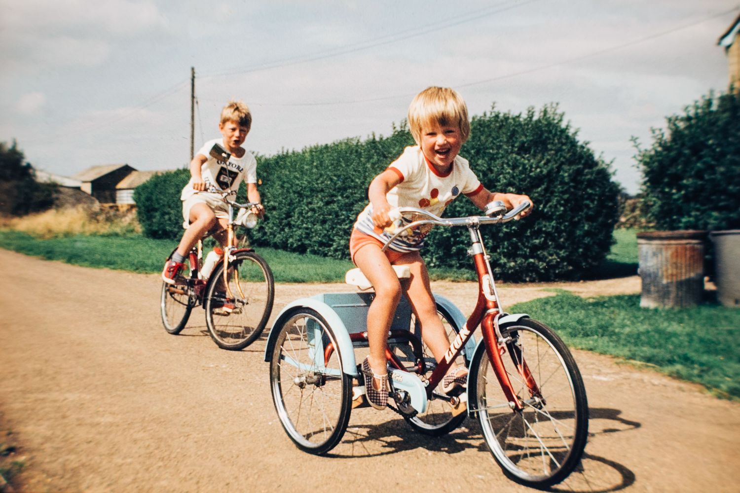 Cat aged four riding a bike with her brother while growing up in the English countryside