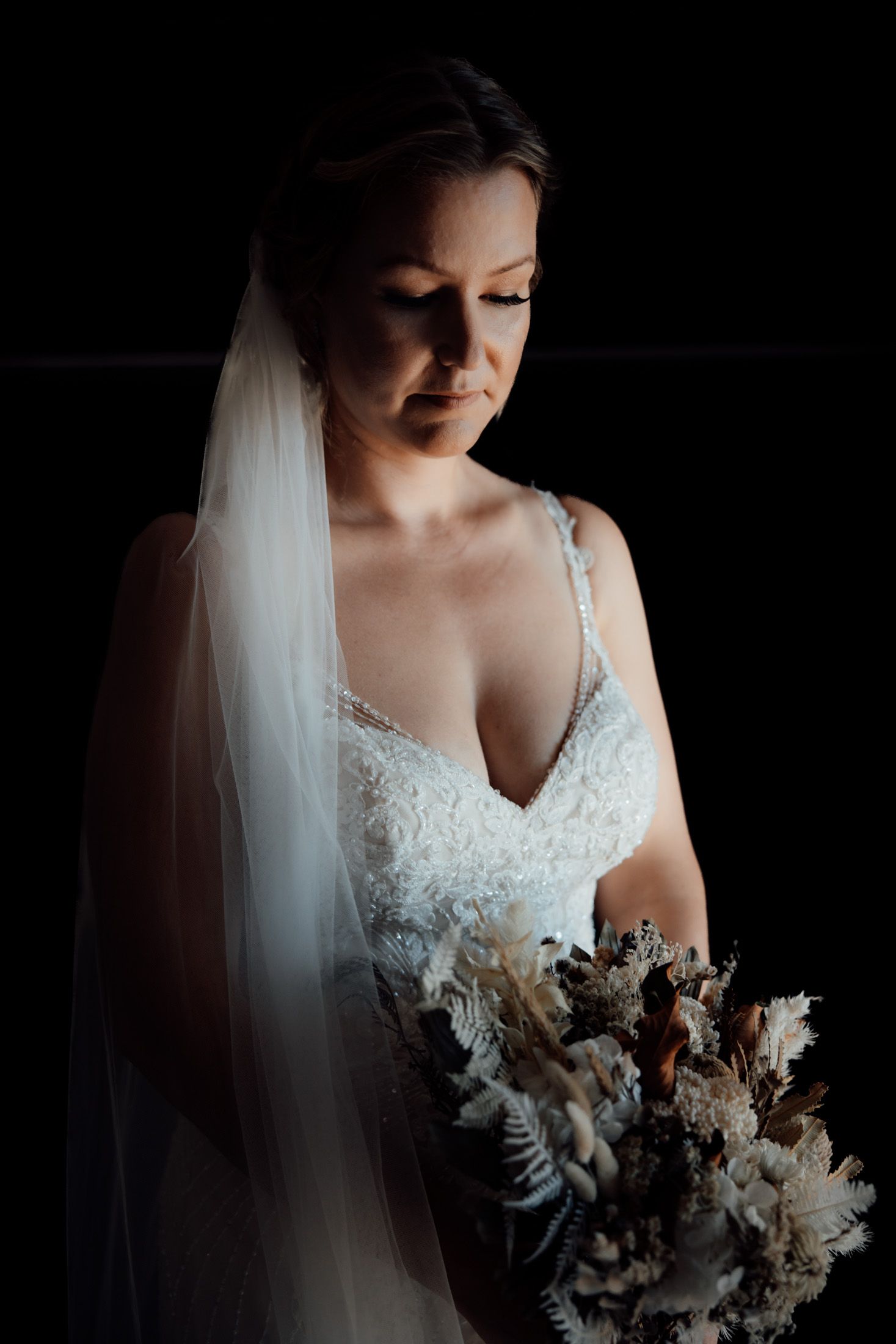 bride portrait showing wedding dress details and dried floral bouquet with window light