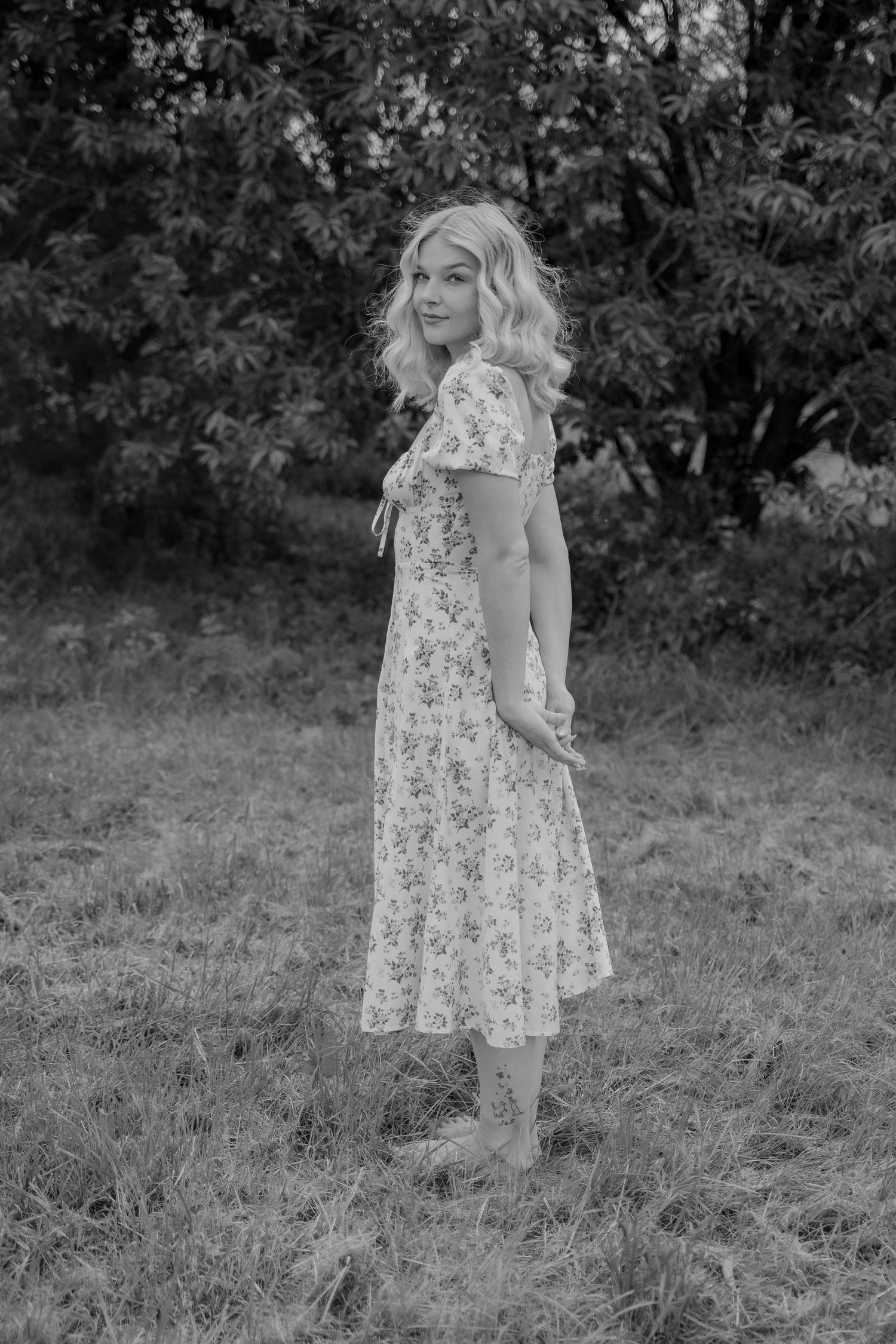Black and white photo series showing a person in a floral dress walking through a grassy outdoor setting.