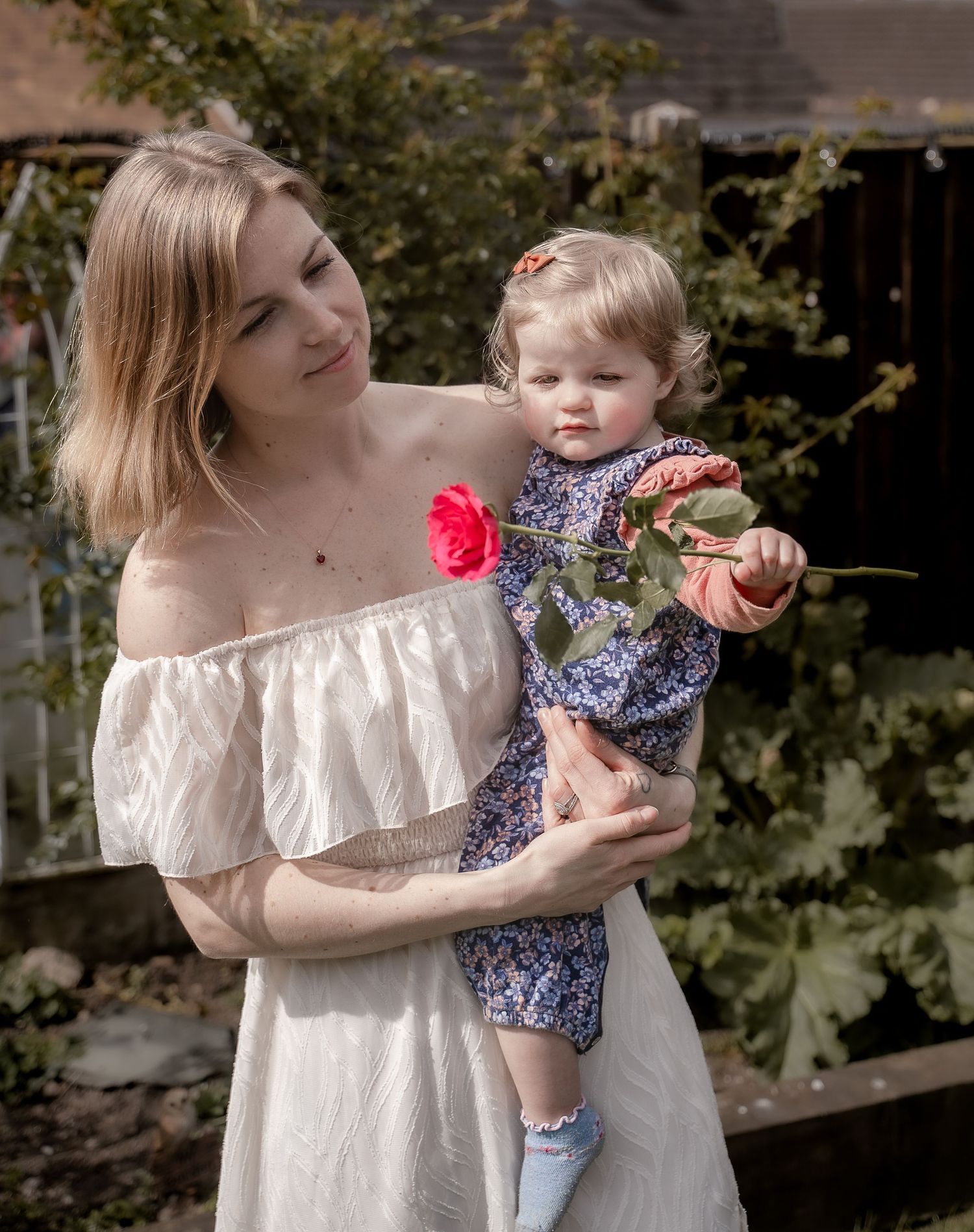 A mother and child share sweet moments together outdoors while enjoying cupcakes in a garden setting.