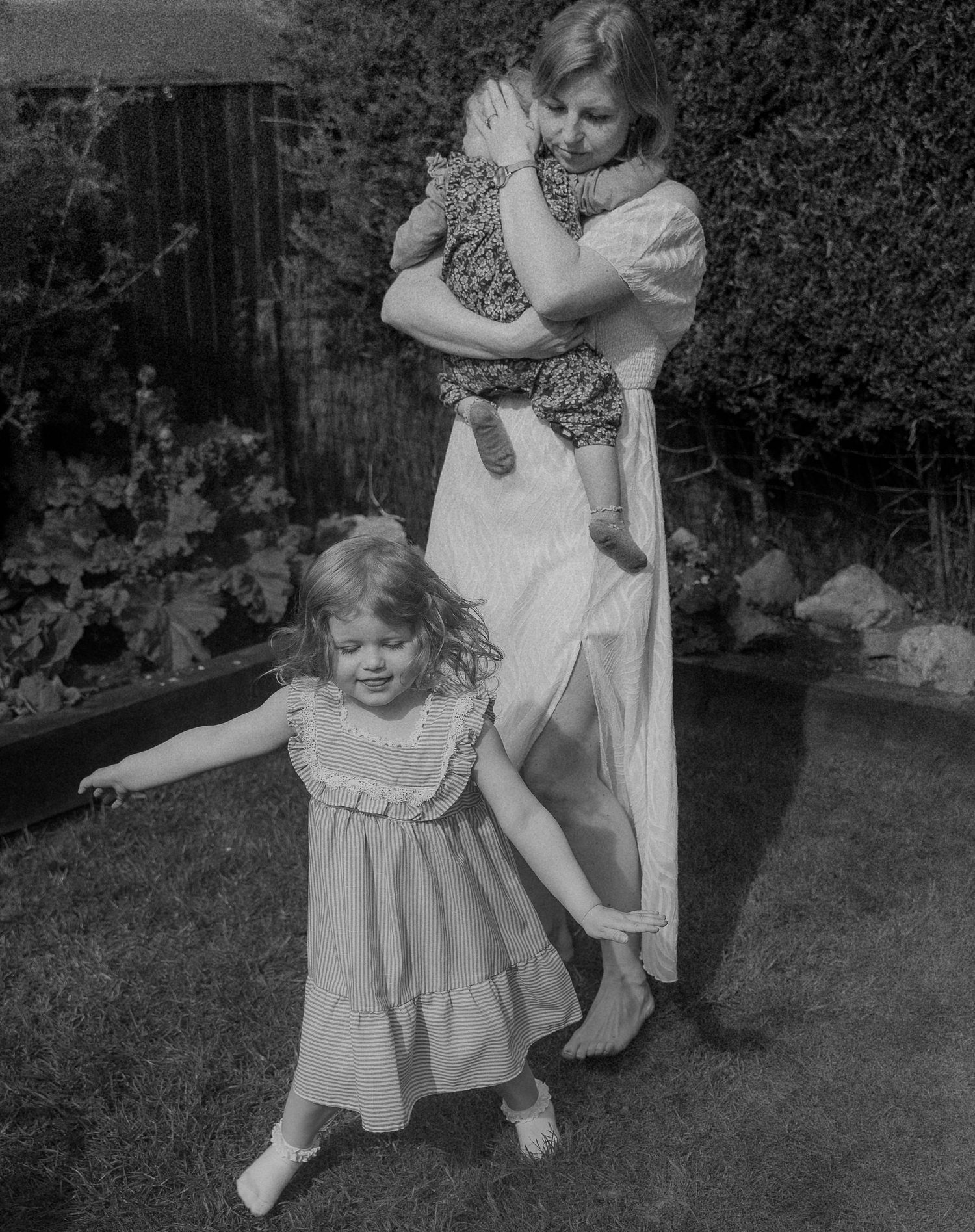 A black and white photo sequence showing children playing and dancing in a backyard garden setting.