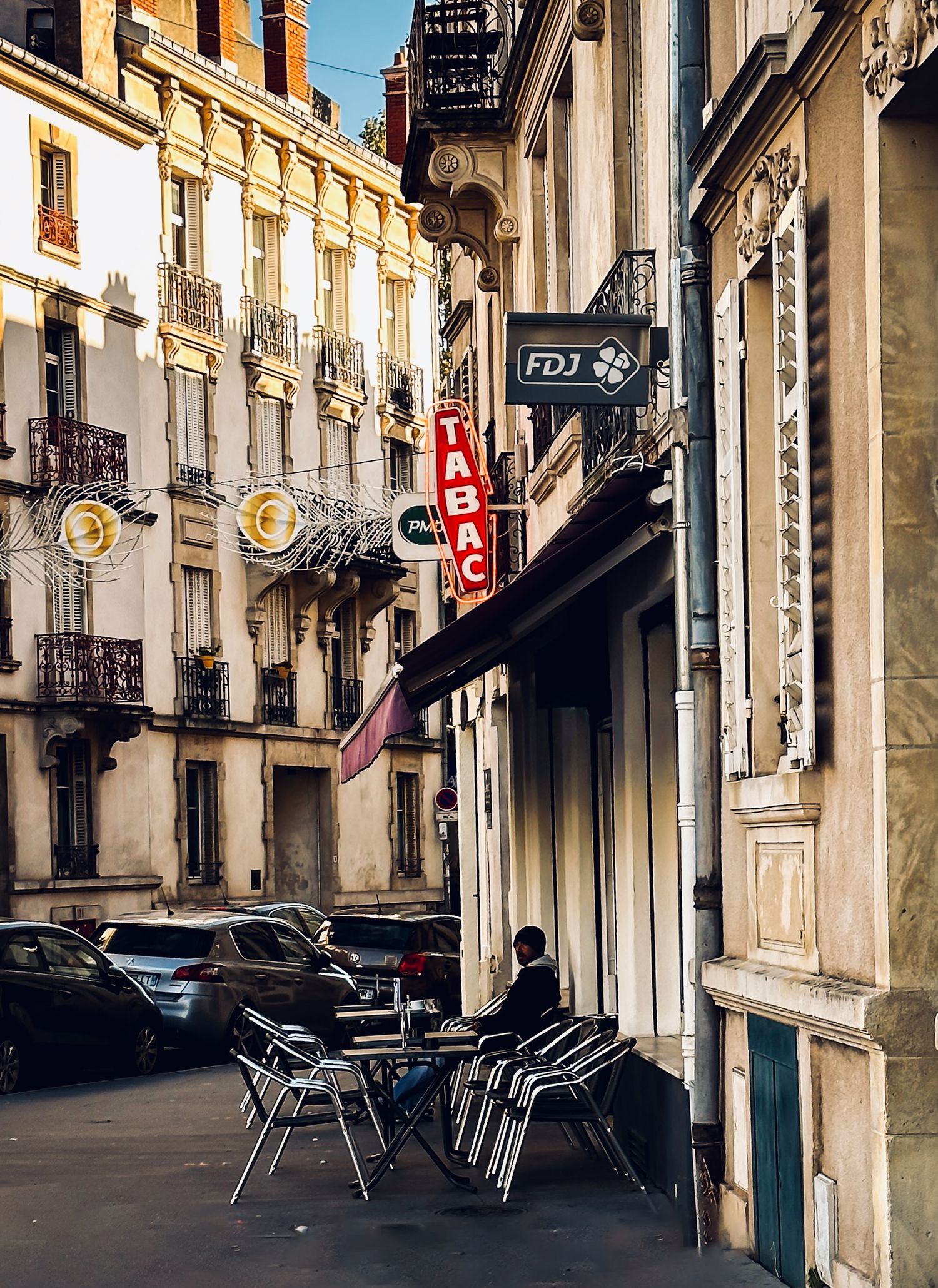 Charming European street view with classic architecture and sidewalk cafe seating.