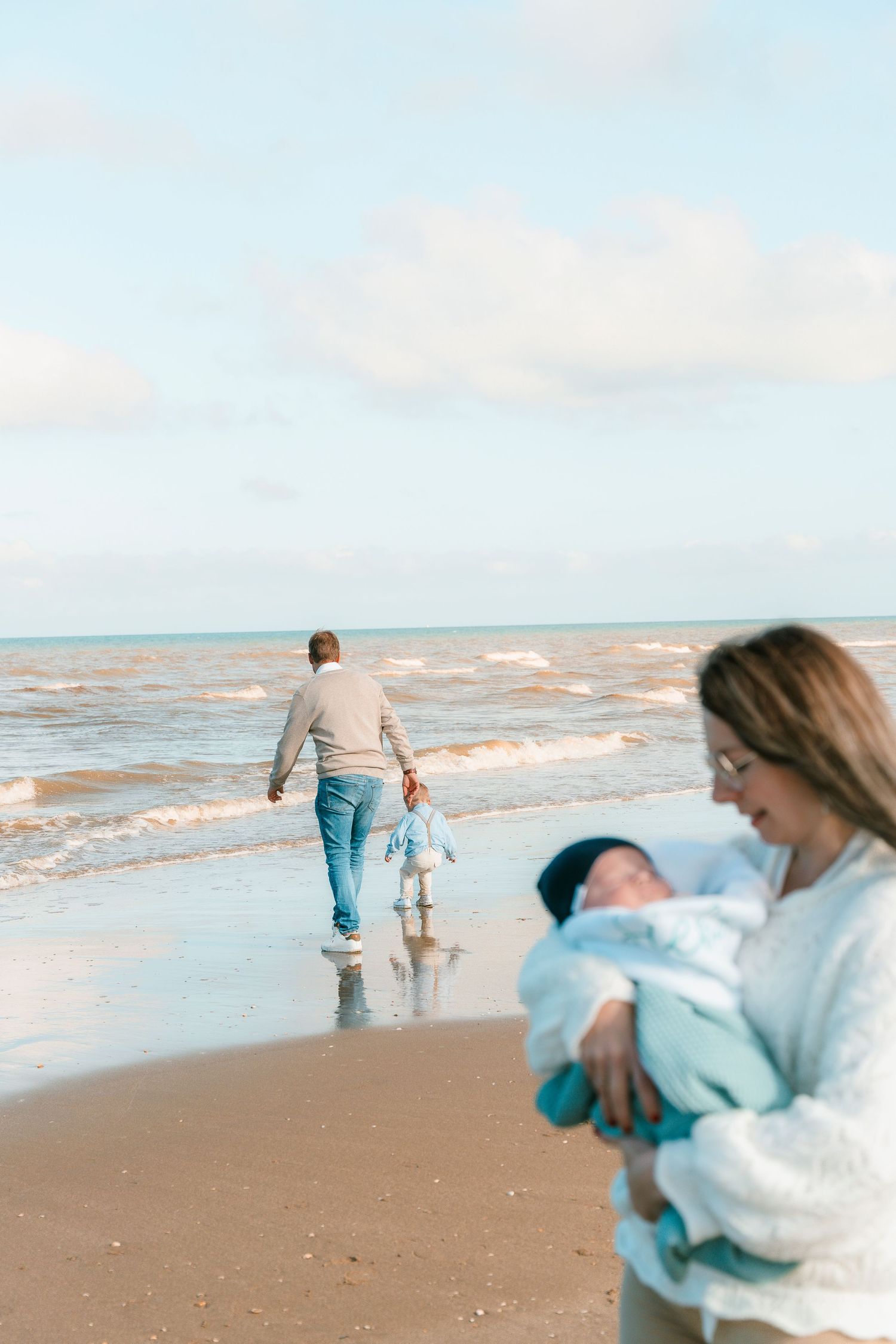 Family enjoying a beach day together with waves crashing in the background.