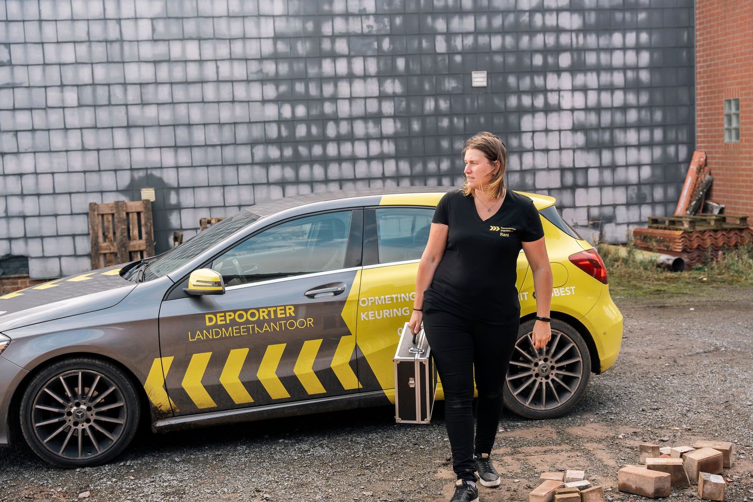 Professional standing by yellow and black striped service vehicle with company branding.