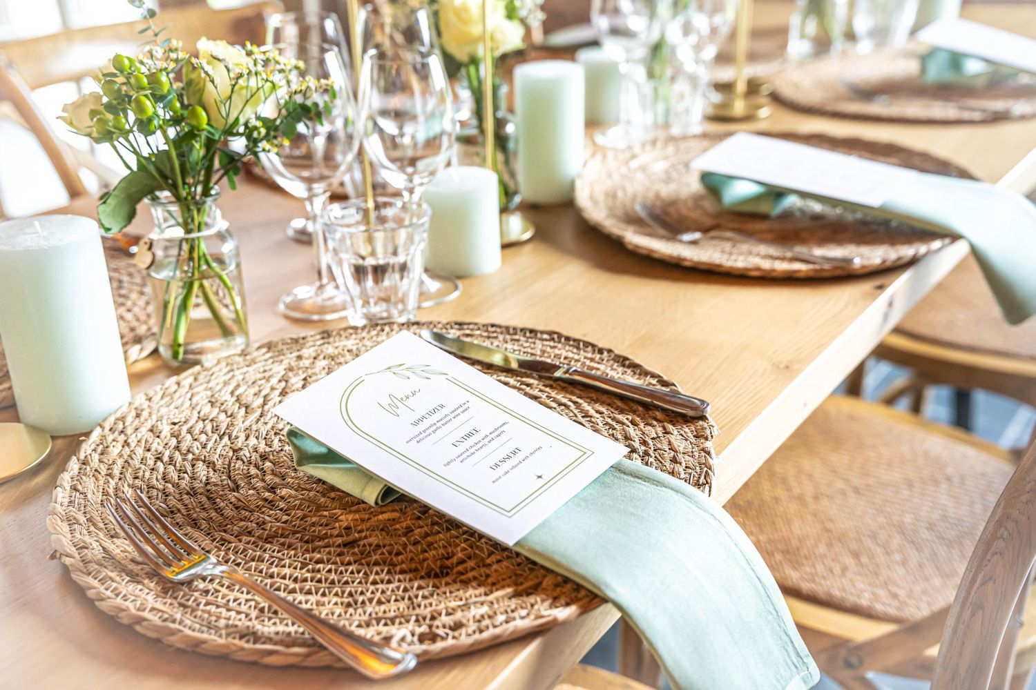Elegant table setting with woven placemats, mint accents, and fresh flower centerpieces.