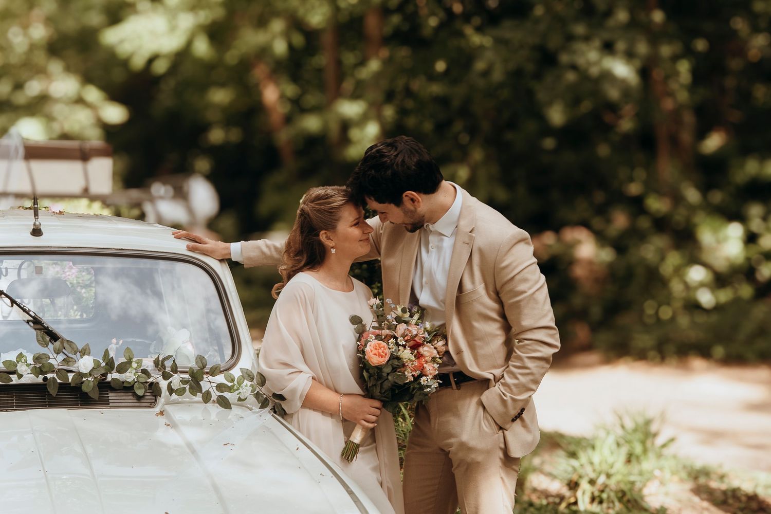 A romantic couple embraces and shares tender moments during their autumn wedding celebration in a sun-dappled outdoor setting.