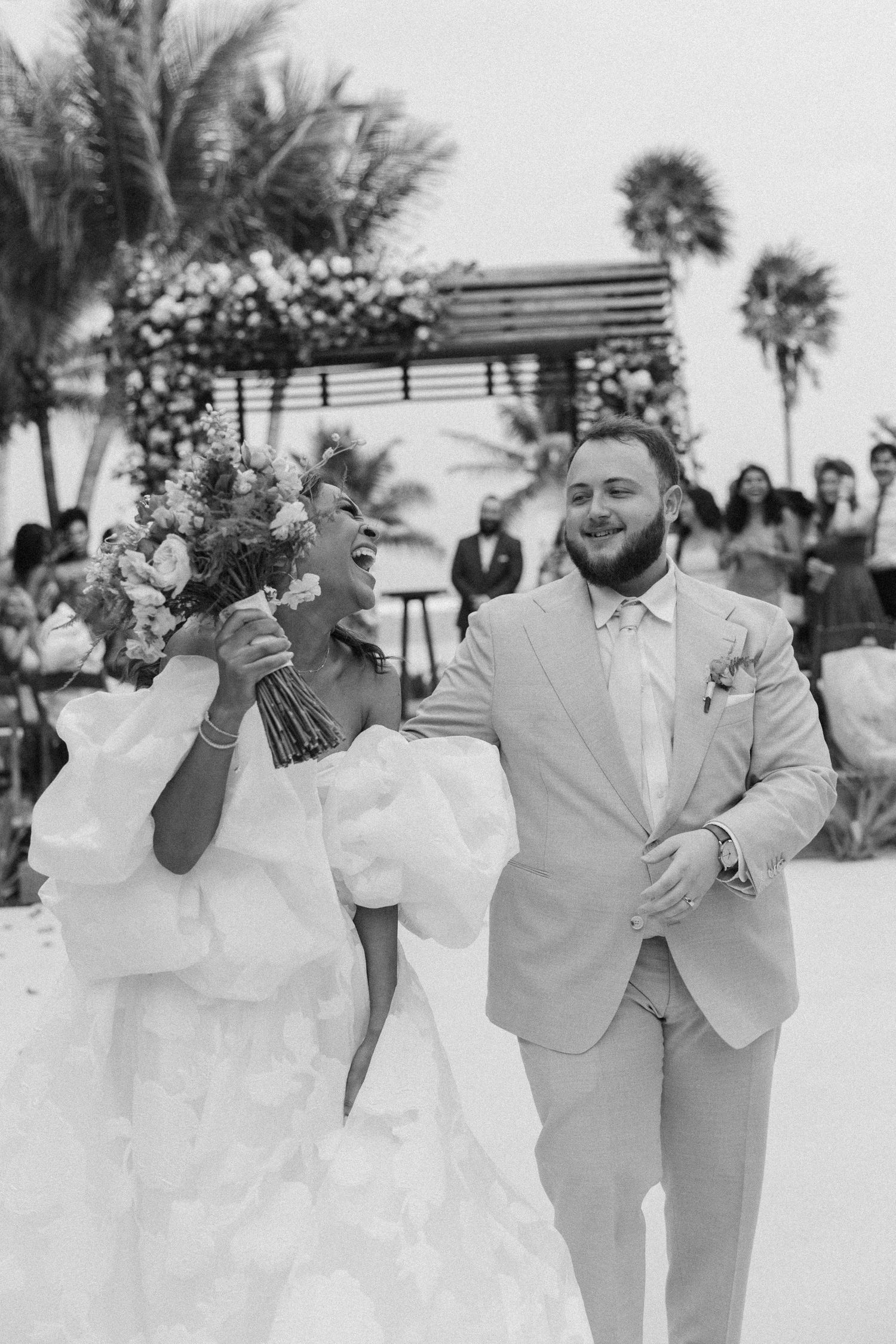 A black and white photo series showing joyful moments between a couple in wedding attire dancing on a beach.