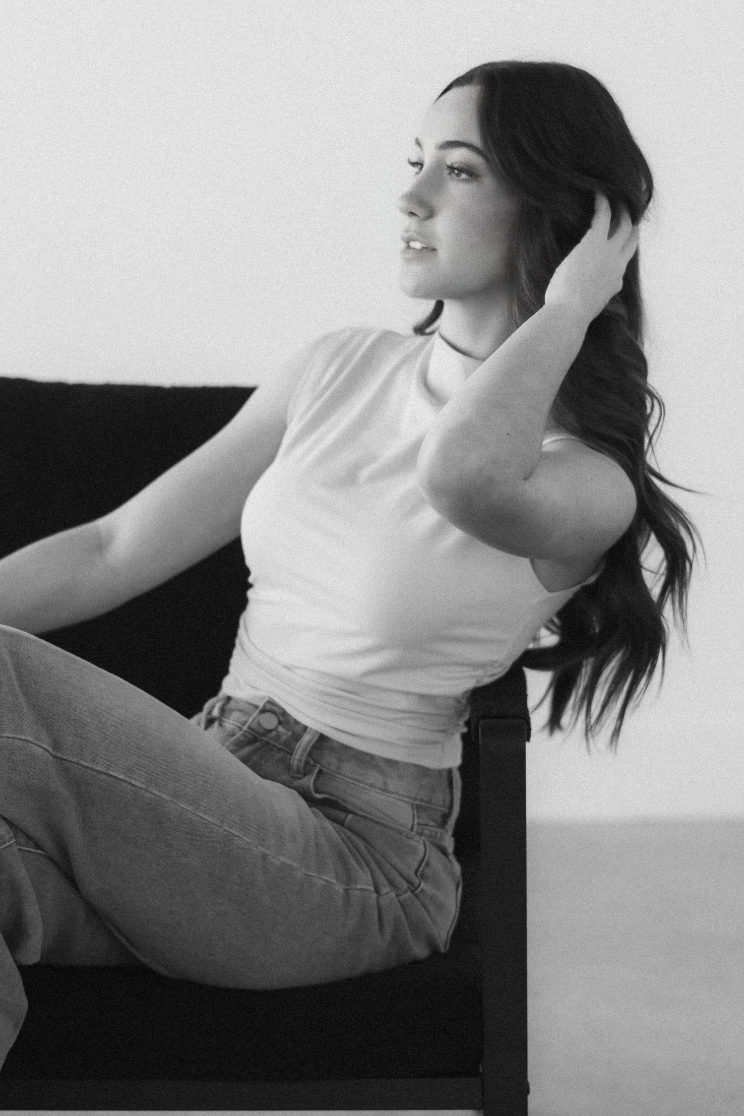 A series of black and white photos showing a person in a white tank top and jeans moving dynamically against a light background.