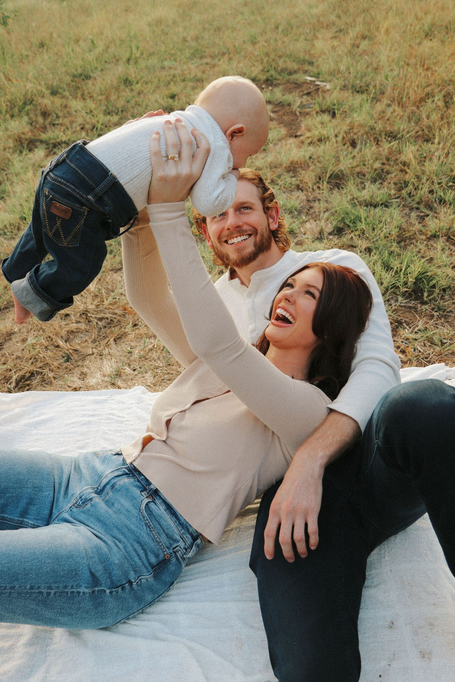 A joyful family moment on a blanket in a grassy field.