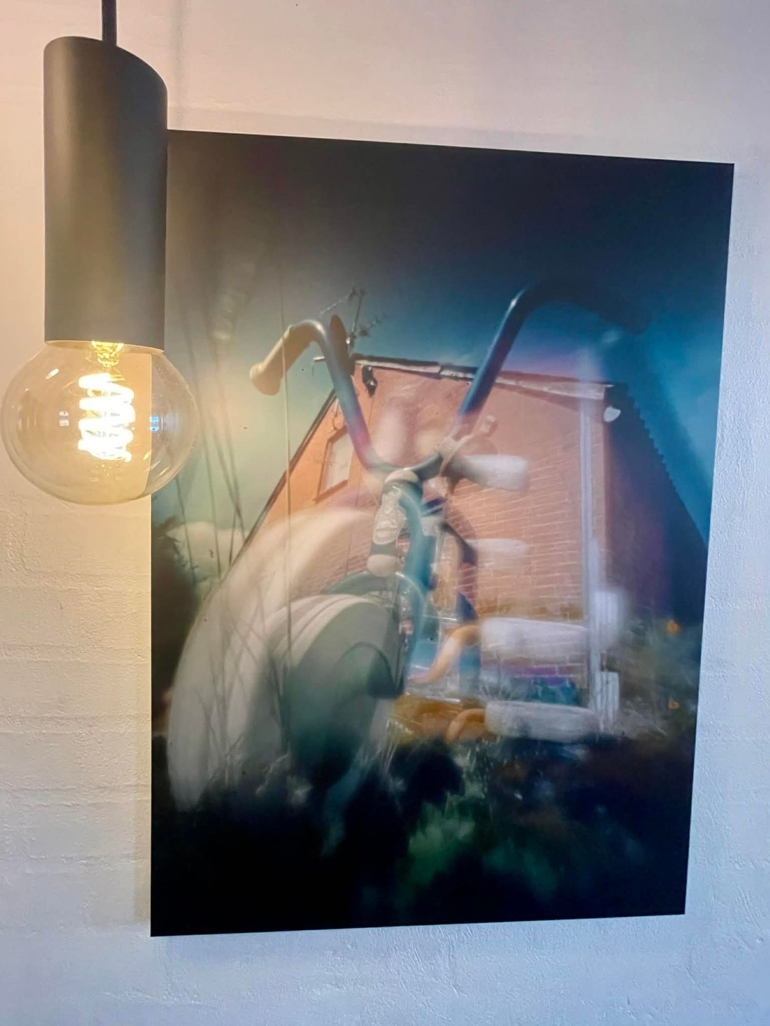 Fotokunst visende en trehjulet cykel foran en bygning