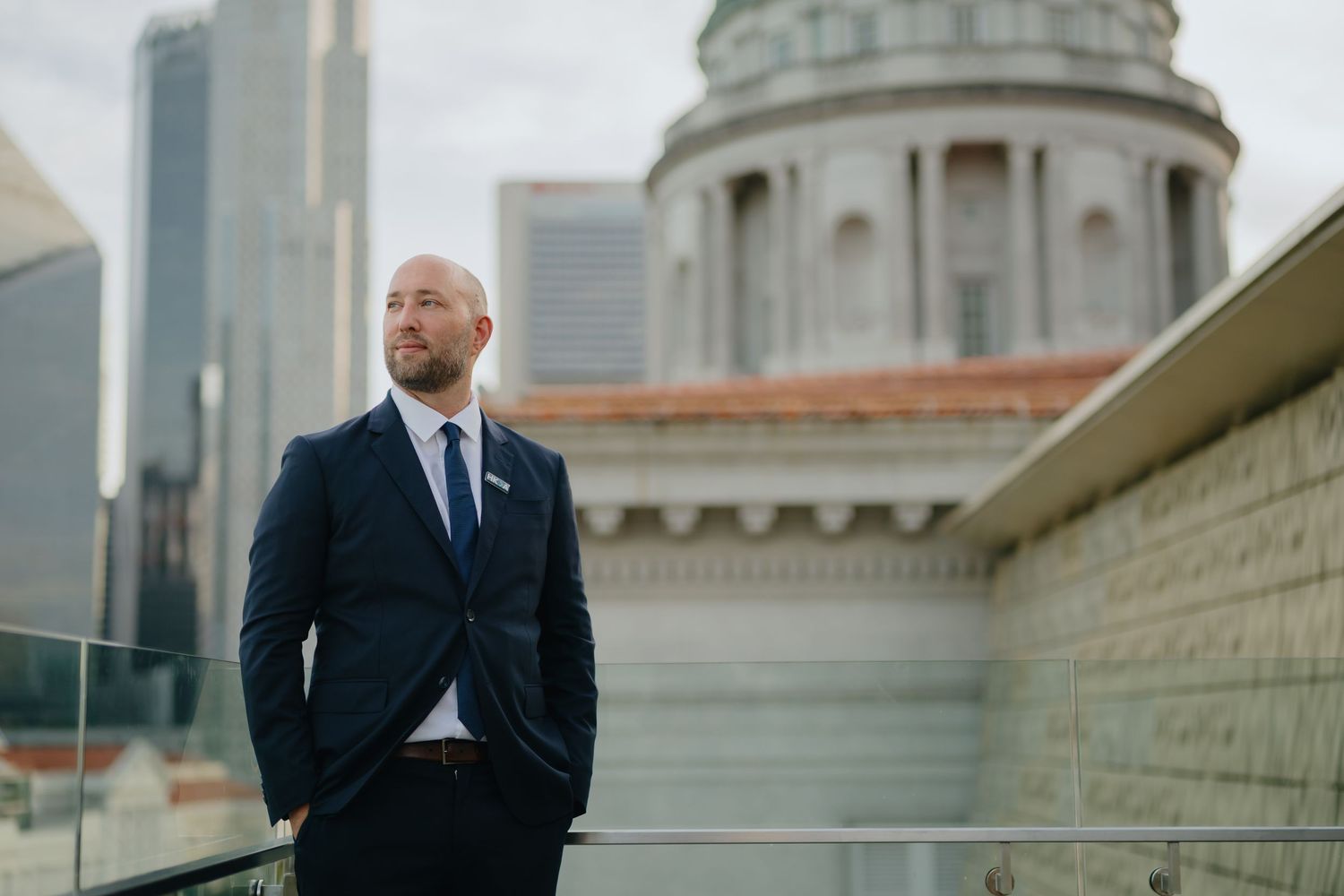 A split image showing a person in a dark suit walking outside a domed government building with columns.