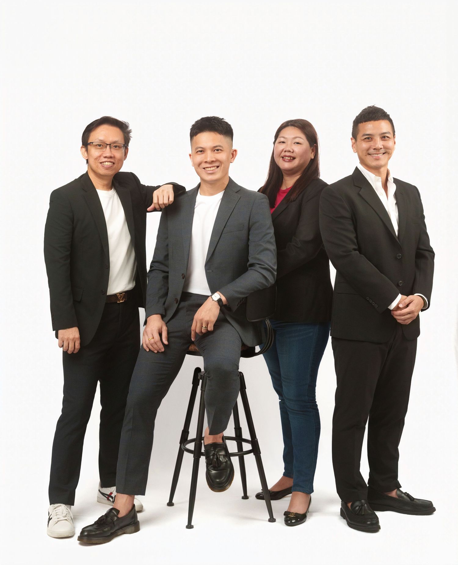 Professional group photo of businesspeople in dark suits arranged casually in a row against a white backdrop.