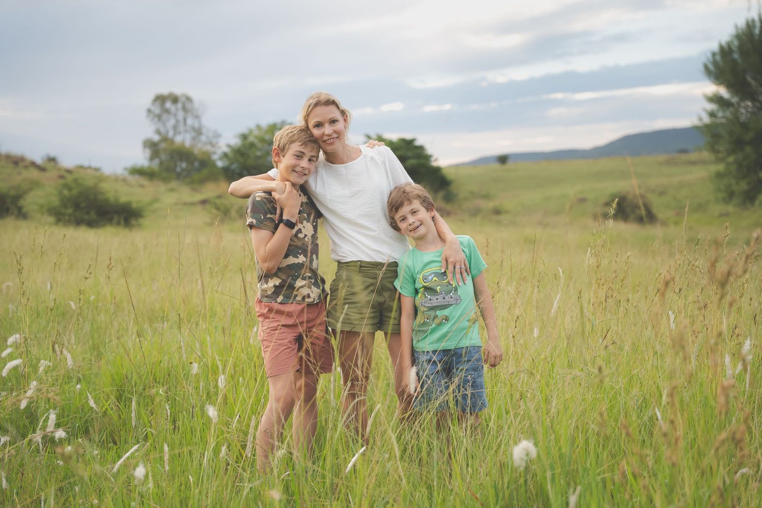 Mom with her boys in a field of long grass, content family hug.