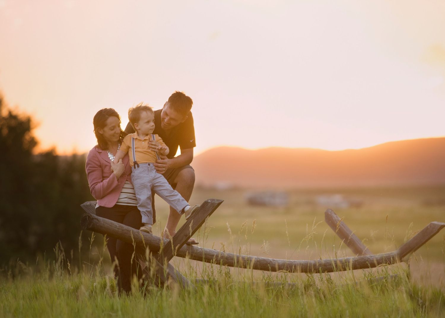 Family silhouetted on a fence at sunset