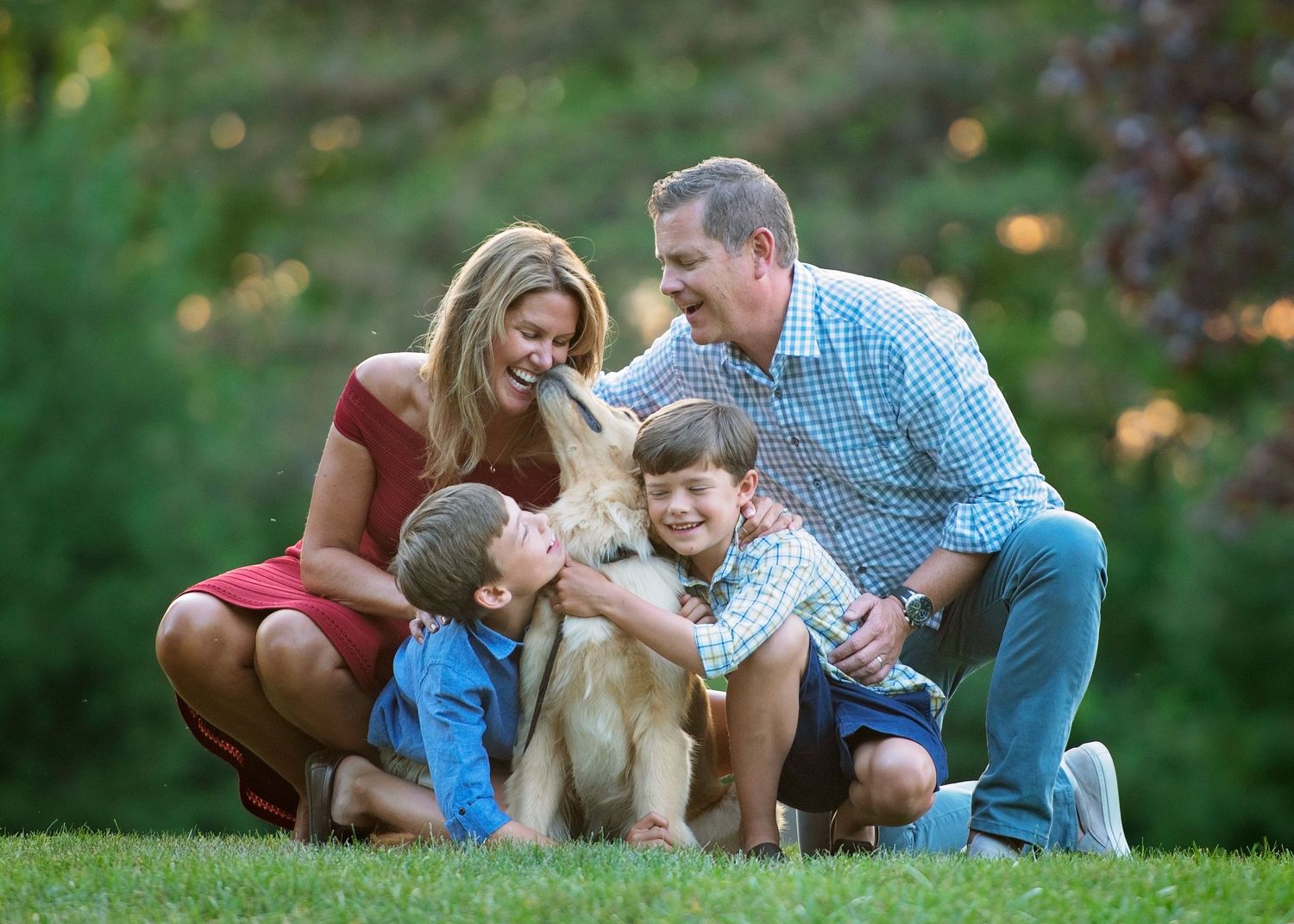 Family kneeling in the yard with their dog