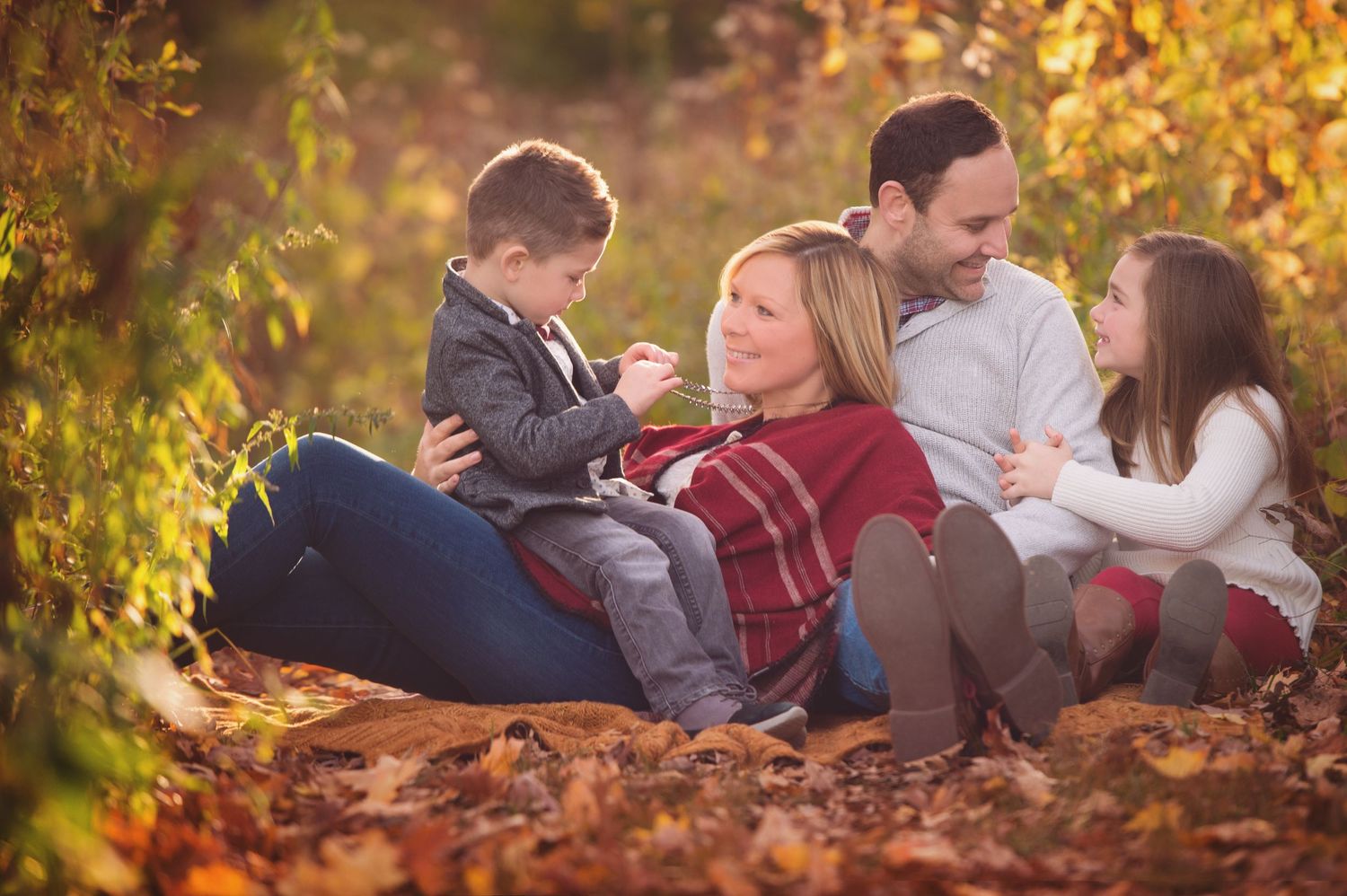 Family of four snuggled together in autumn leaves