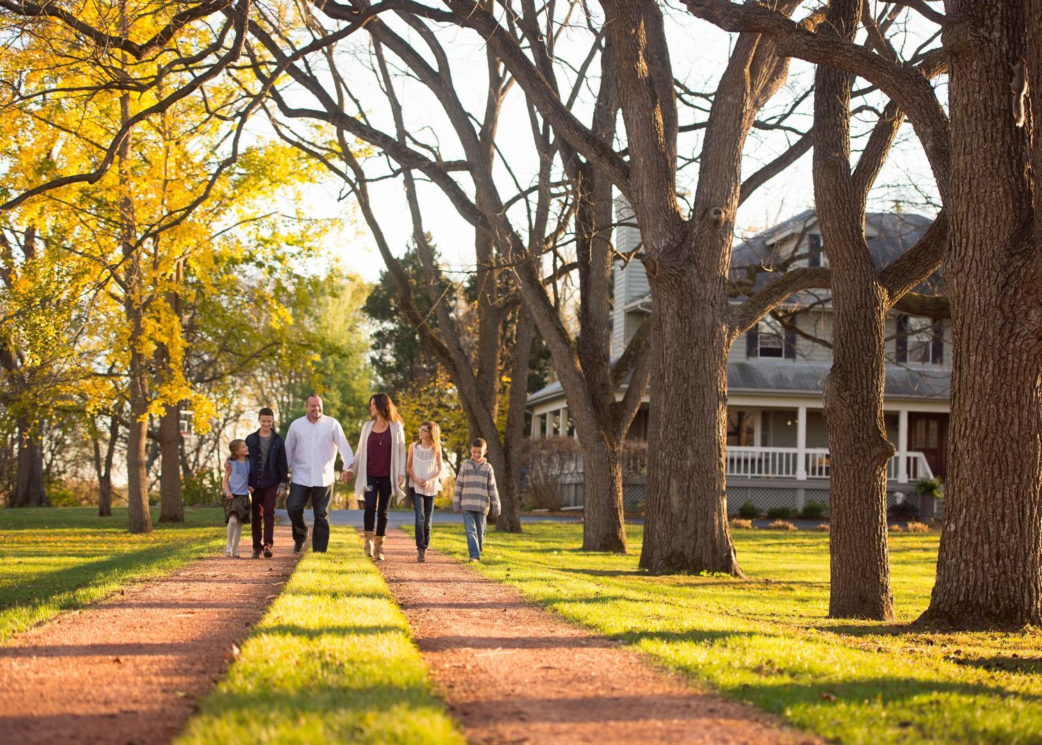 Family walking a tree-lined drive in autumn